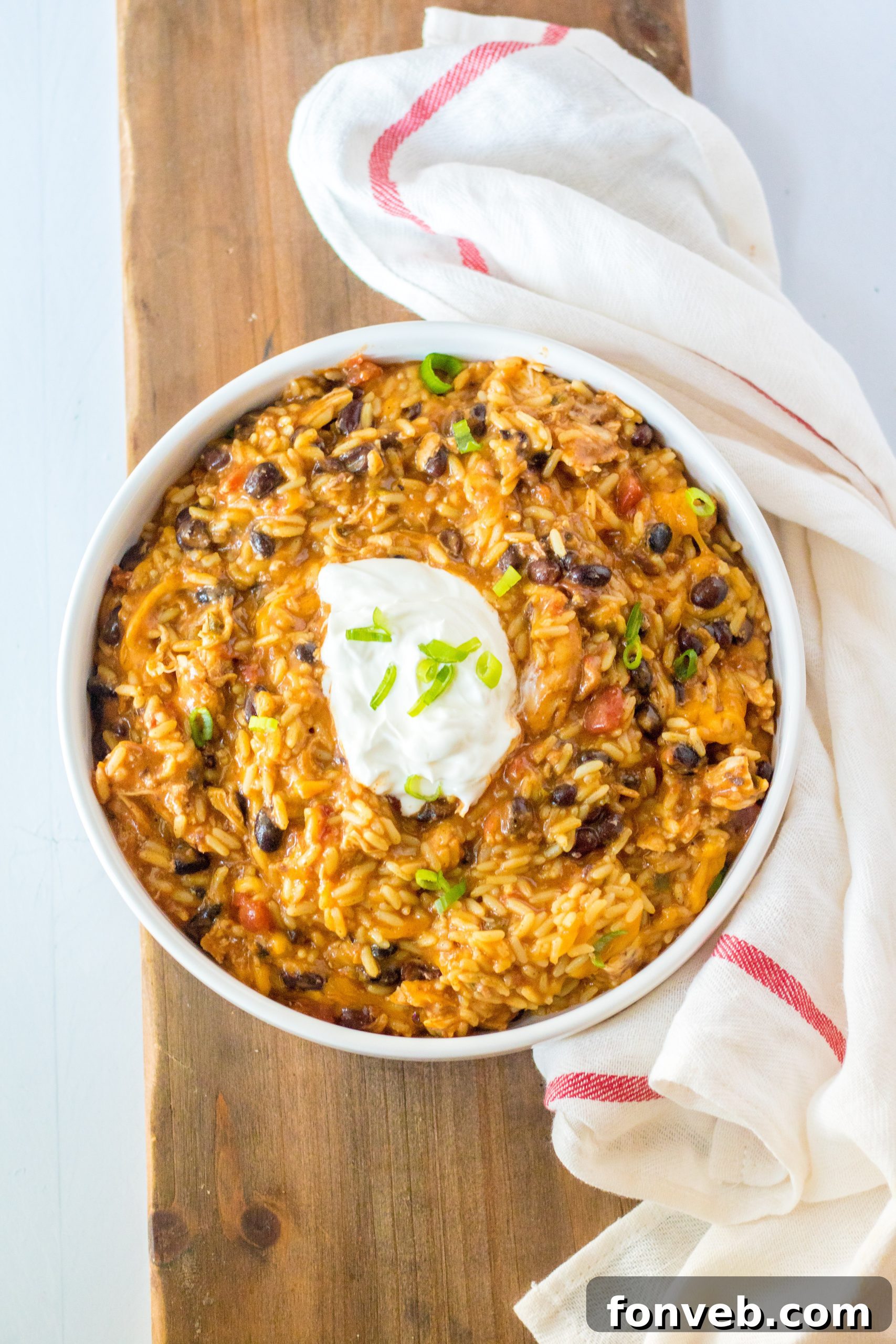 Creamy Slow Cooker Cheesy Chicken Taco Rice 12 A bowl of Slow Cooker Cheesy Chicken Taco Rice topped with sour cream and cilantro
