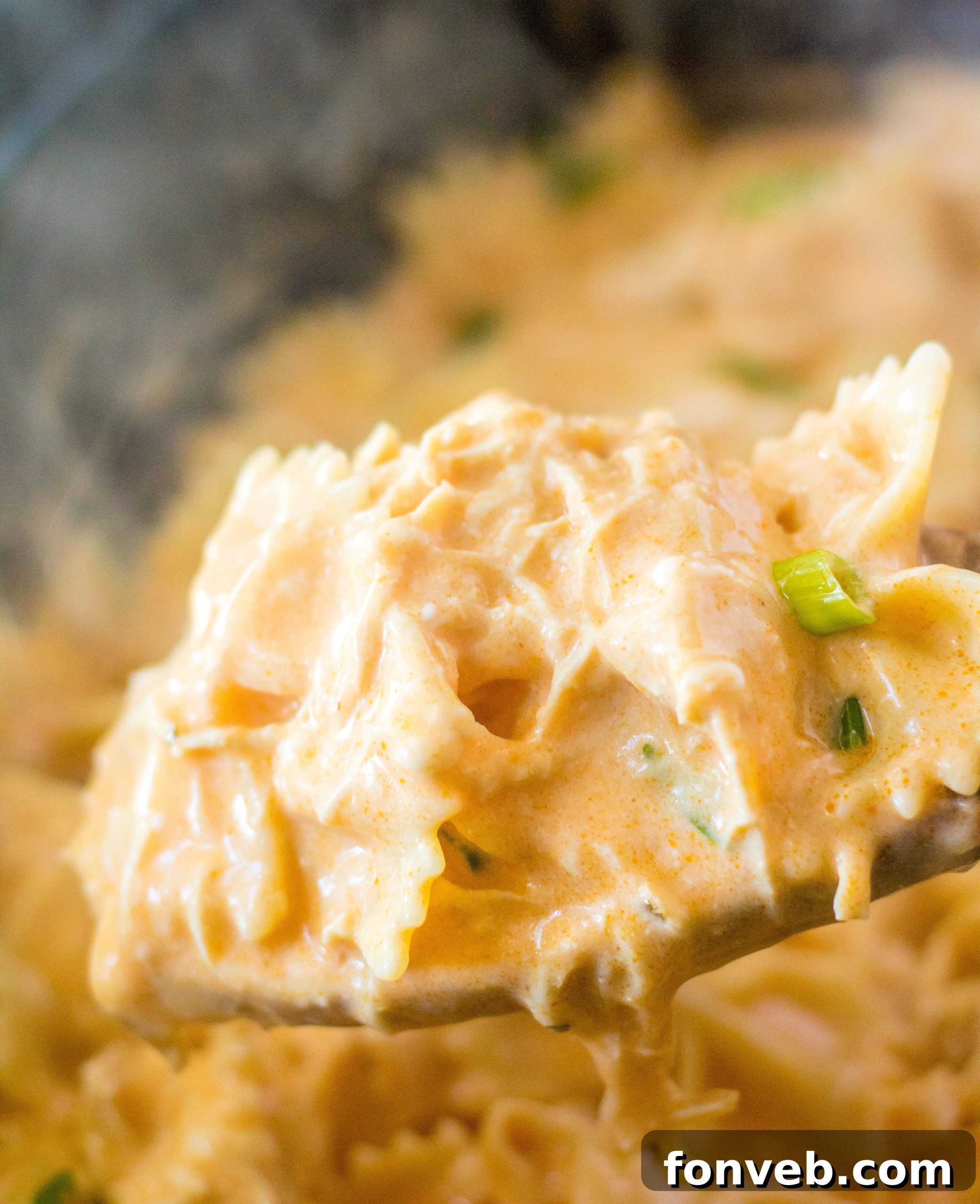 Slow cooker buffalo chicken pasta garnished with fresh parsley and a dollop of blue cheese.