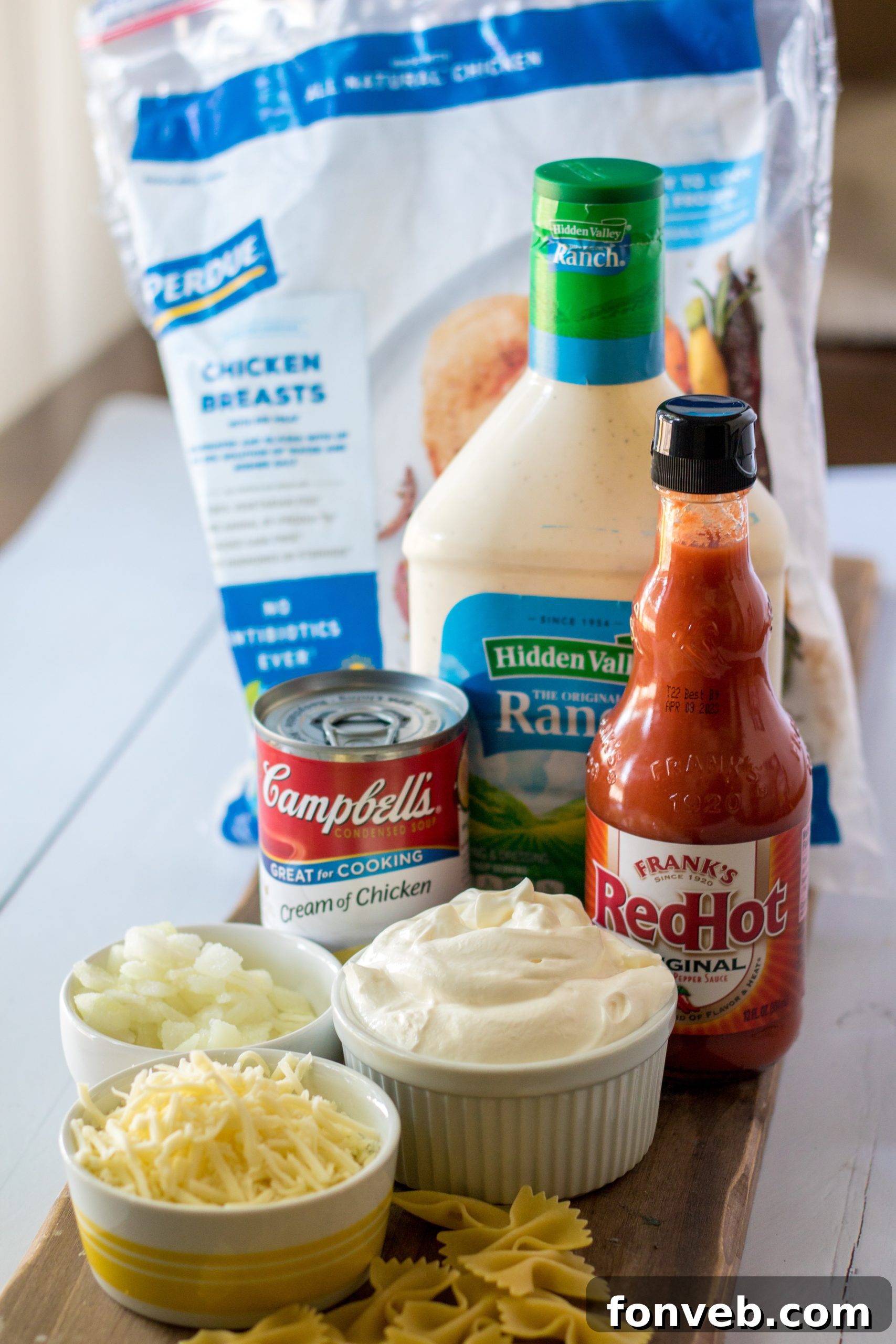 A top-down view of a large serving bowl filled with slow cooker buffalo chicken pasta, garnished with fresh herbs.