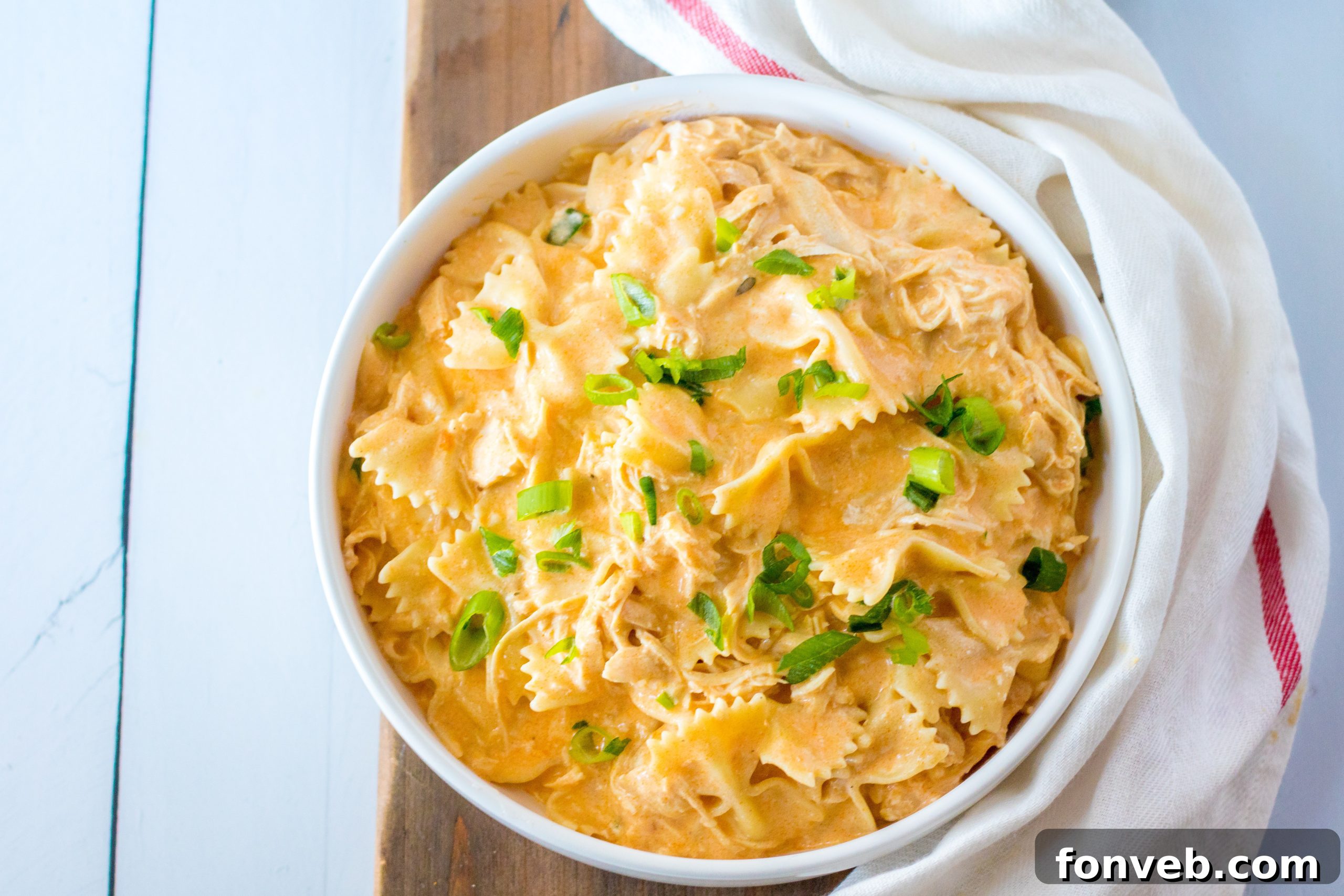 Close-up of shredded buffalo chicken mixed with creamy sauce in a slow cooker.