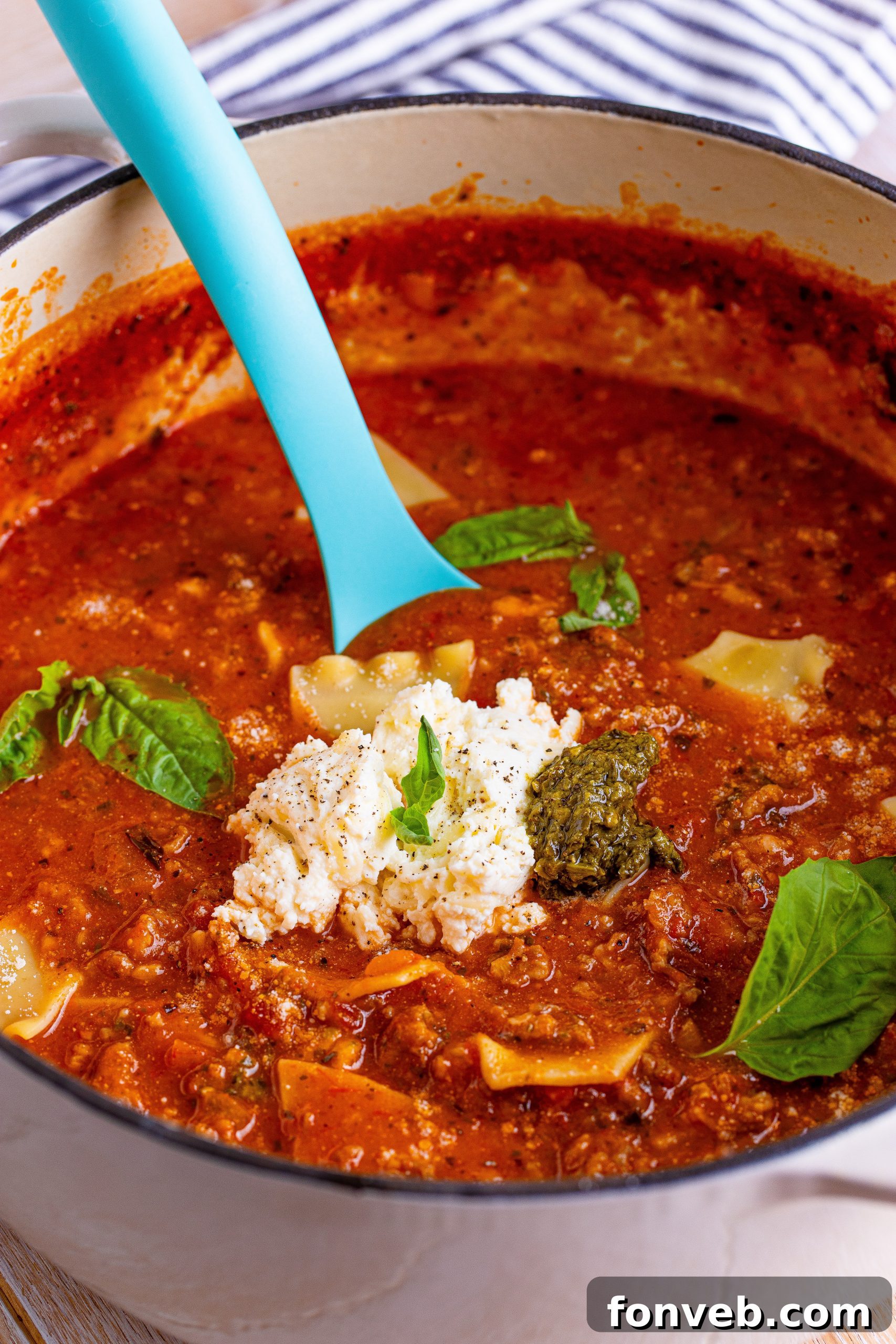 A bowl of Lasagna Soup being topped with cheese