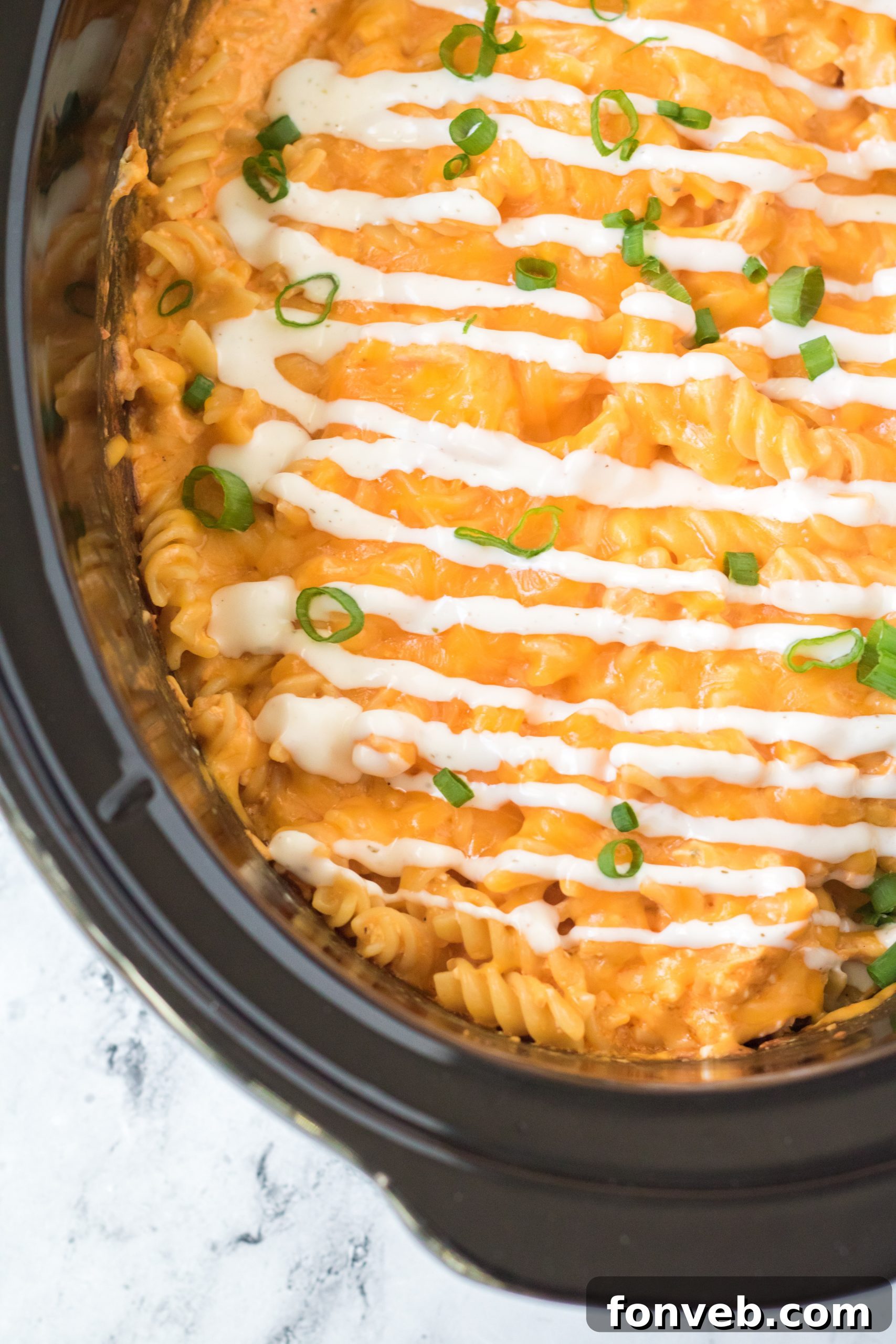 Tangy Slow Cooker Buffalo Chicken Mac and Cheese 14 Close-up of Slow Cooker Buffalo Chicken Mac & Cheese with a variety of garnishes, including green onions and blue cheese.