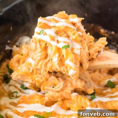 Tangy Slow Cooker Buffalo Chicken Mac and Cheese 16 Slow Cooker Buffalo Chicken Mac & Cheese in a white bowl, garnished with green onions.