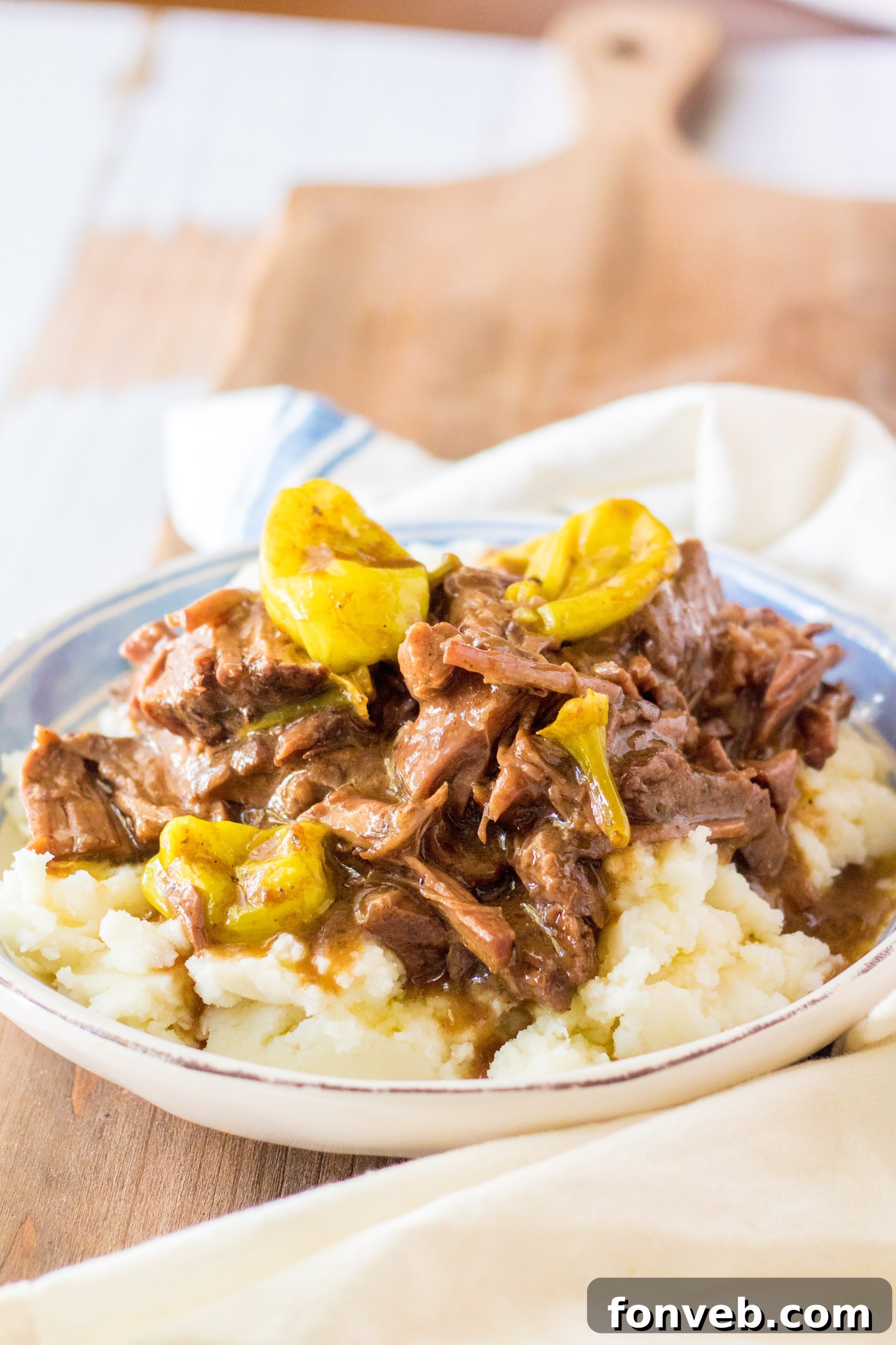 Melt-in-Your-Mouth Slow Cooker Mississippi Pot Roast 7 A stick of butter resting on top of a chuck roast inside a slow cooker.