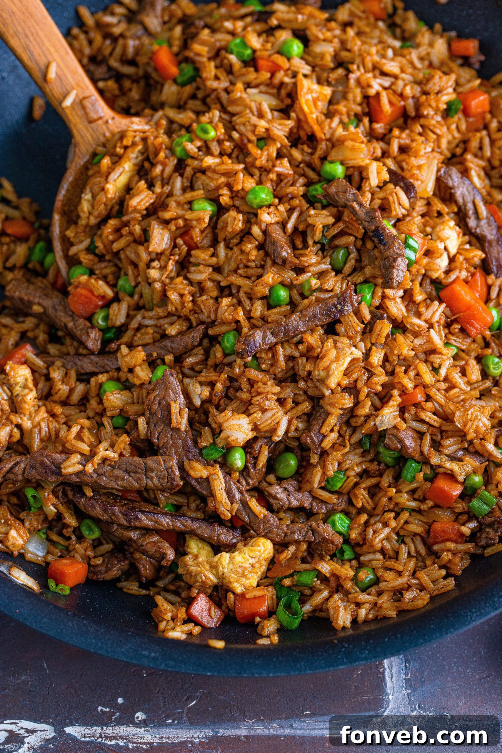 A chef's skillful perspective of preparing Beef Fried Rice in a wok, emphasizing the cooking process.