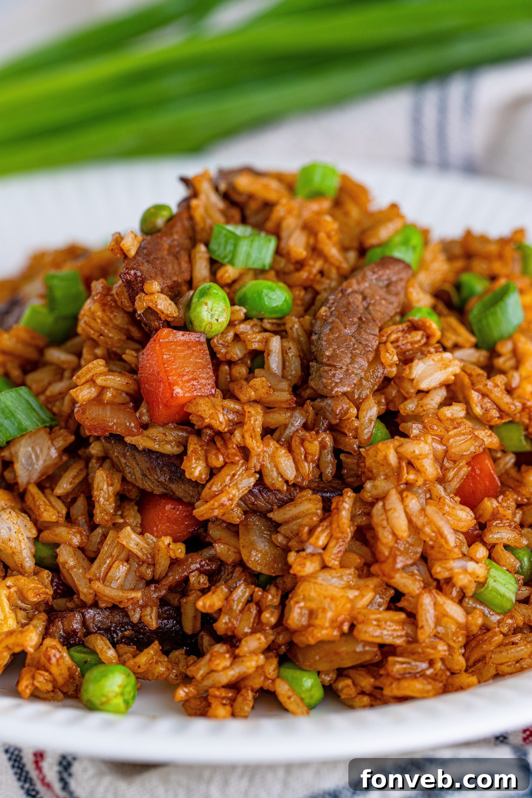 A curated selection of fresh ingredients for Beef Fried Rice, including sauces, steak, and vegetables, laid out on a kitchen counter.