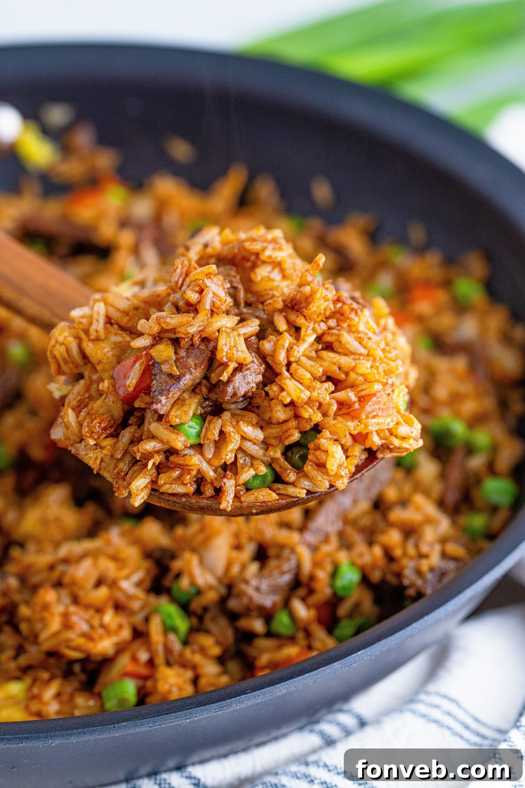 A chef expertly stir-frying Beef Fried Rice in a traditional wok over high heat.