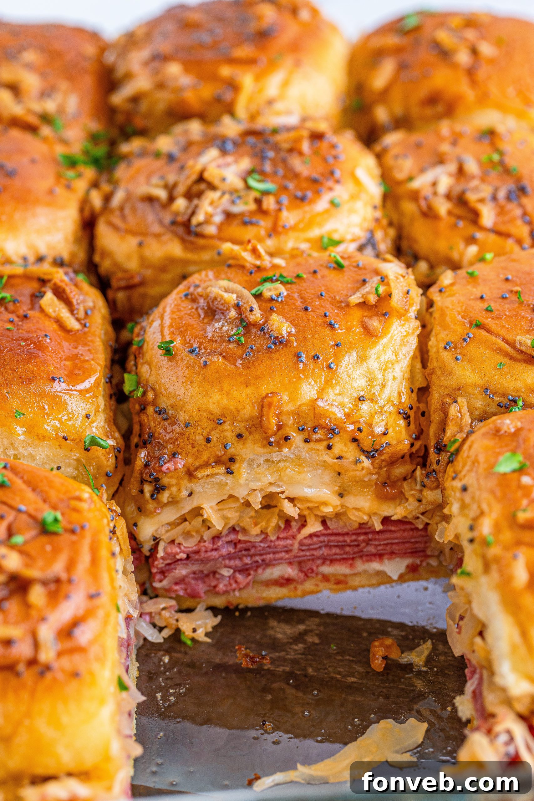 A hand reaching for a Reuben Slider from a plate, highlighting its appetizing look.