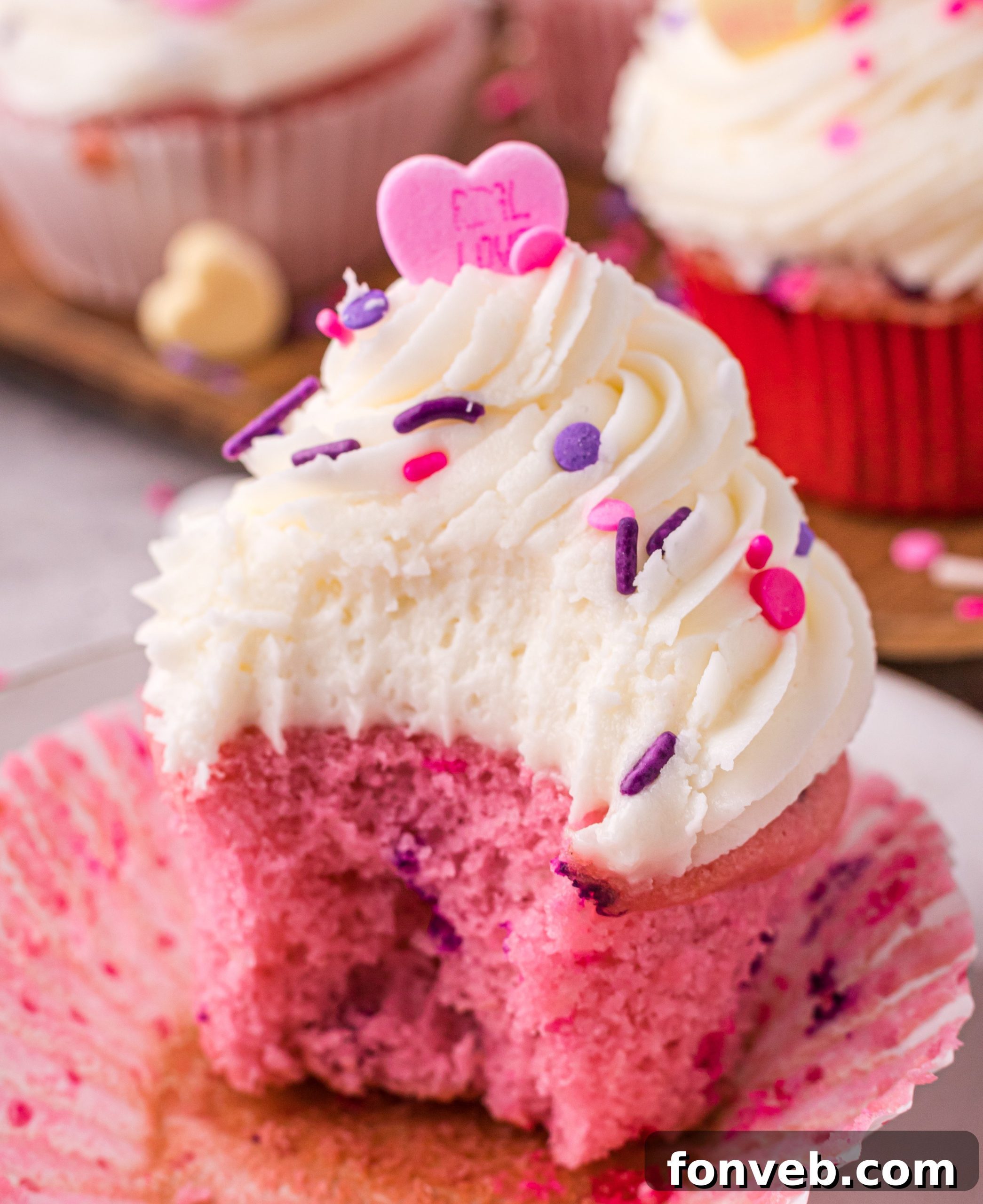 Blushing Velvet Vanilla Cupcakes 2 Close-up of a beautifully decorated pink velvet cupcake with vanilla buttercream and sprinkles, ready for Valentine's Day.