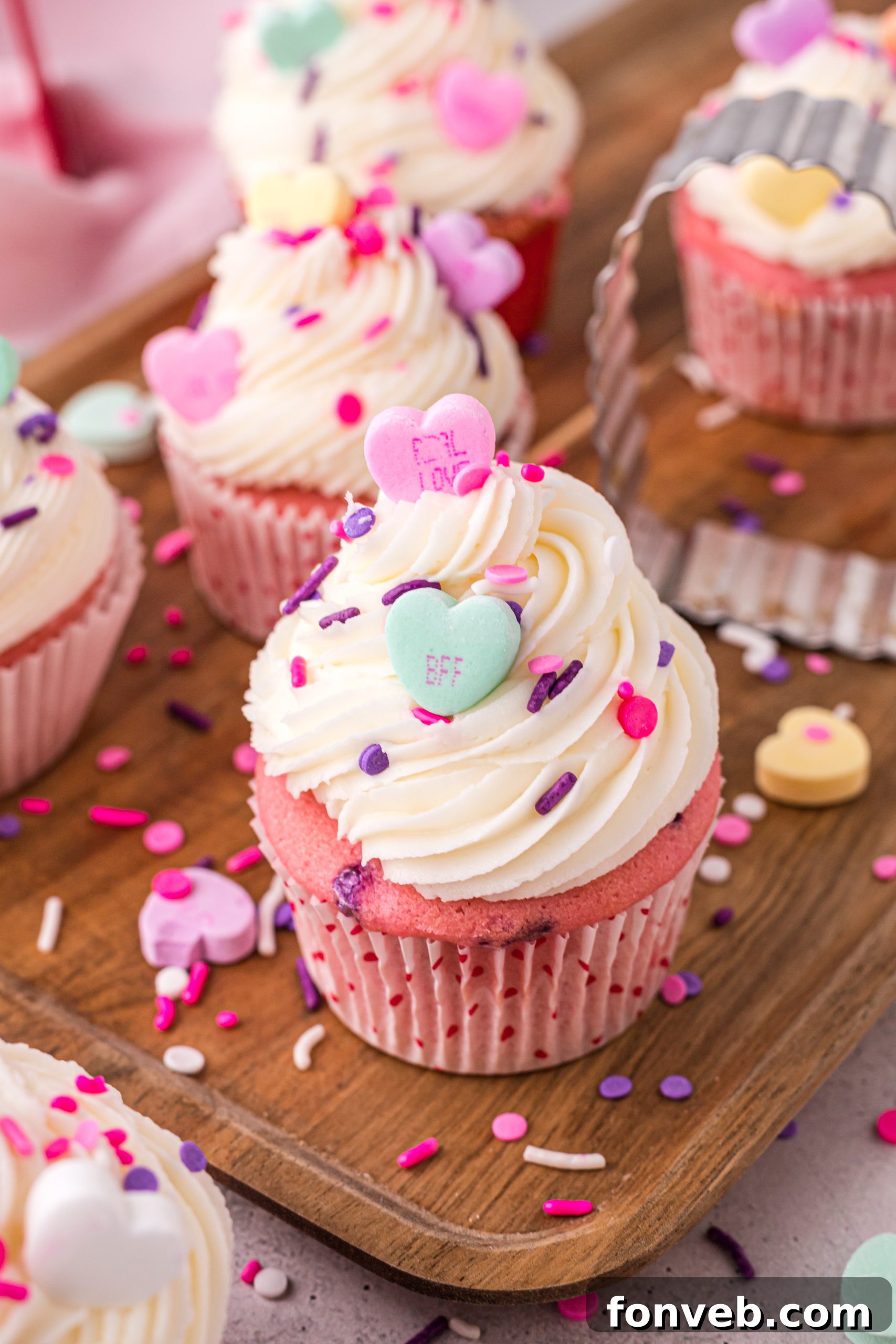 Blushing Velvet Vanilla Cupcakes 11 A collection of pink velvet cupcakes with various frosting designs and colorful sprinkles.