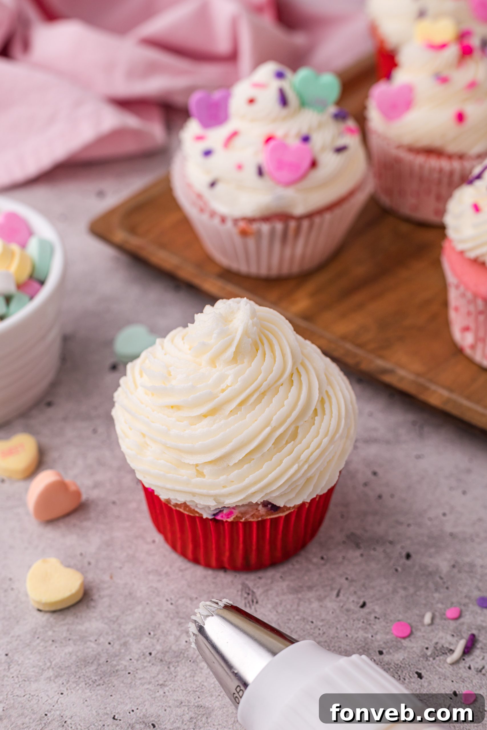 Blushing Velvet Vanilla Cupcakes 4 Top-down view of a single pink velvet funfetti cupcake with swirled vanilla buttercream and a heart candy.