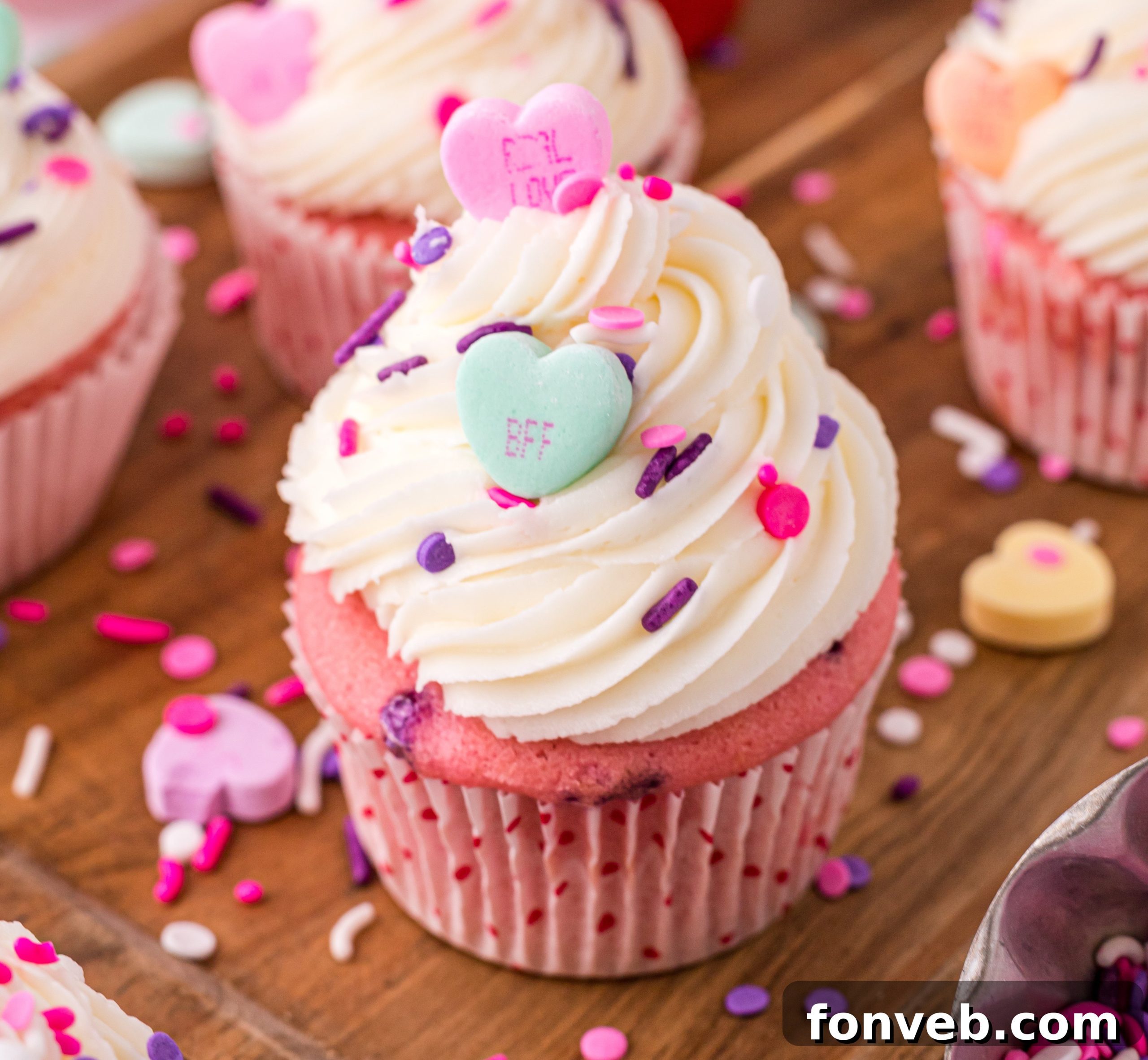 Blushing Velvet Vanilla Cupcakes 5 Ingredients laid out for baking pink velvet cupcakes: cake mix, flour, sugar, eggs, sour cream, vanilla, oil, milk, butter, sprinkles, and food coloring.