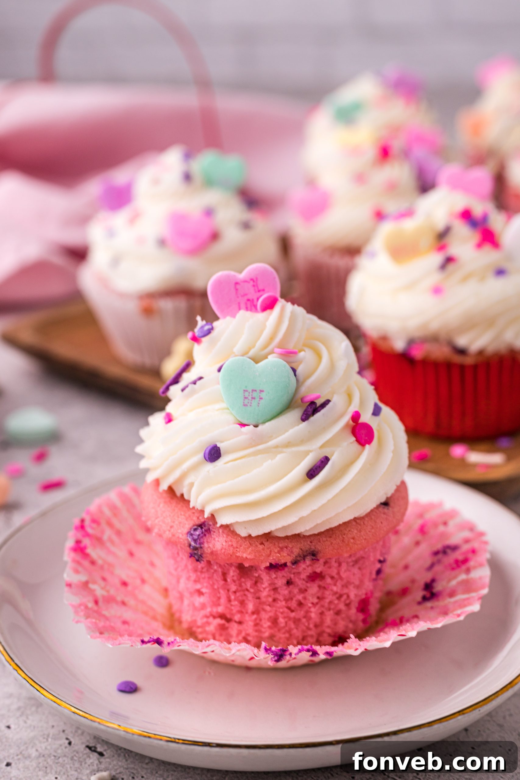 Blushing Velvet Vanilla Cupcakes 7 Close-up of a pink velvet cupcake with a perfect swirl of white vanilla buttercream frosting and colorful sprinkles.