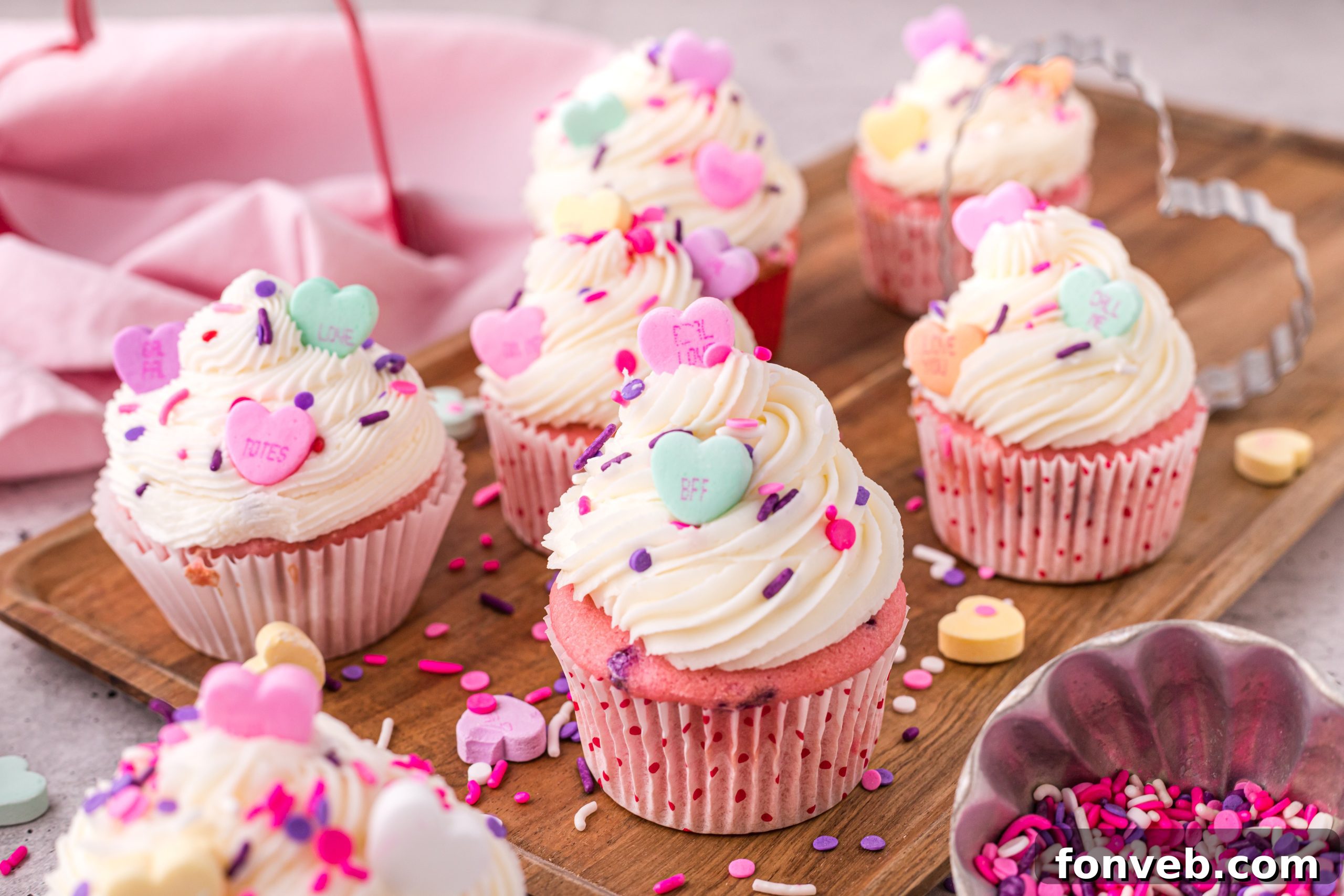 Blushing Velvet Vanilla Cupcakes 9 Several frosted pink velvet cupcakes with pink and white frosting and a variety of sprinkles.