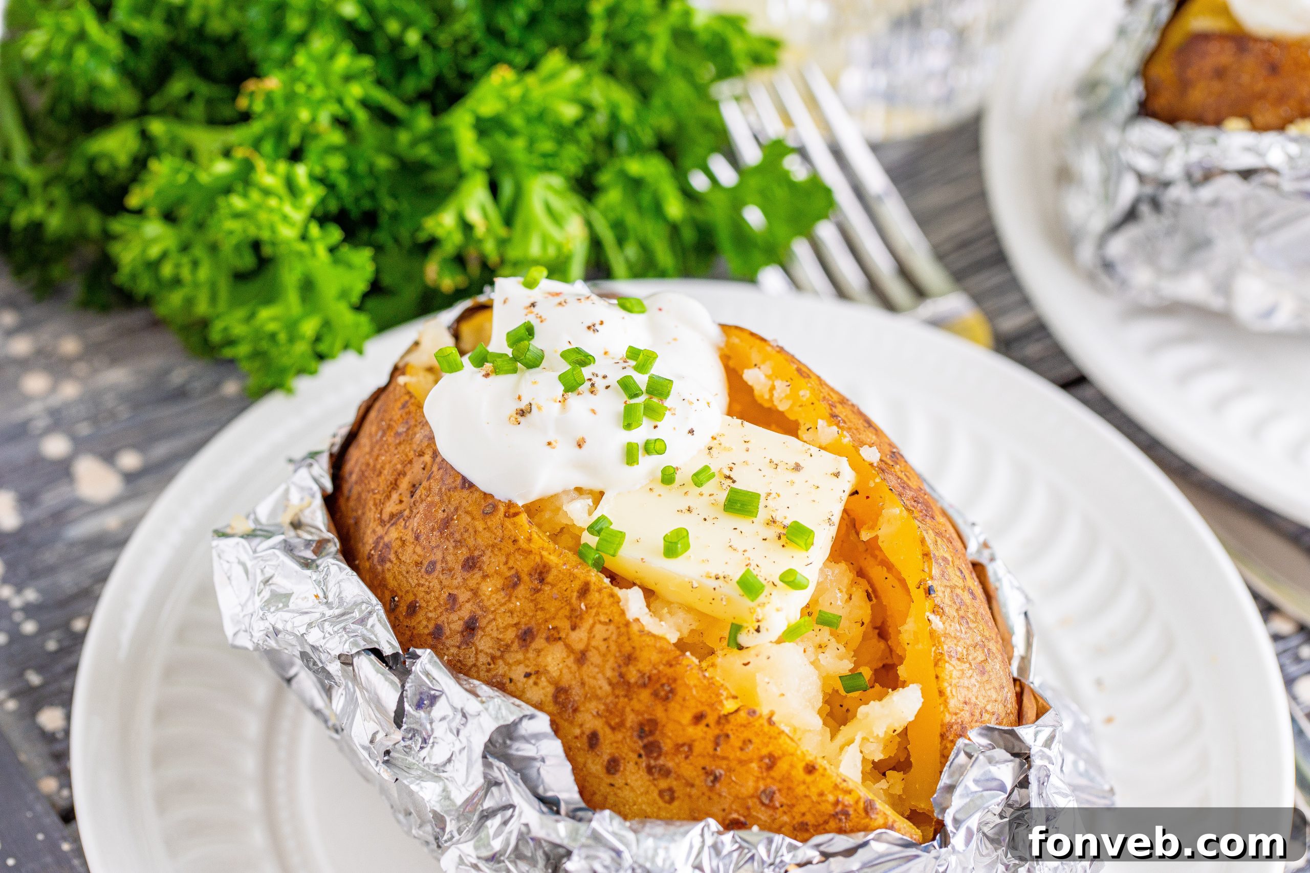 Top view of four perfectly baked potatoes in foil, ready to be unwrapped and garnished