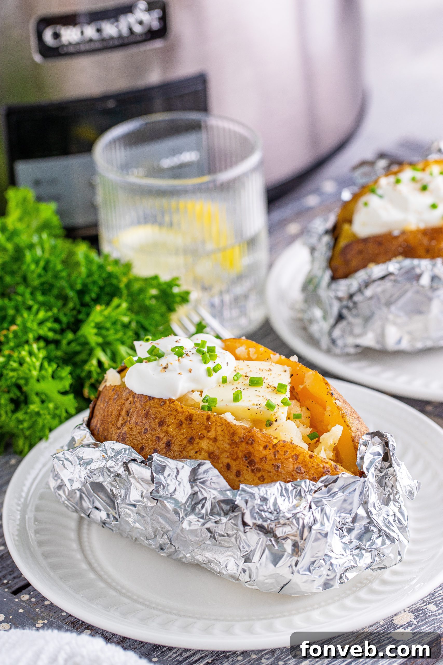 A fork testing the tenderness of a slow cooker baked potato, showing its soft texture
