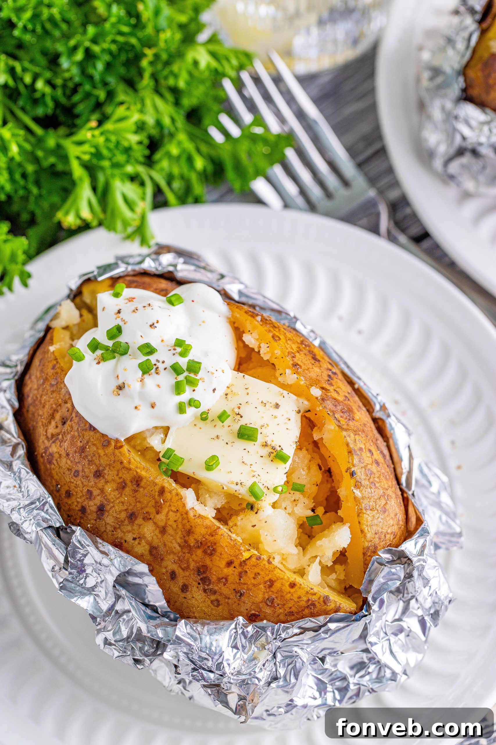 A baked potato unwrapped from foil, with steam gently rising, ready for the addition of butter