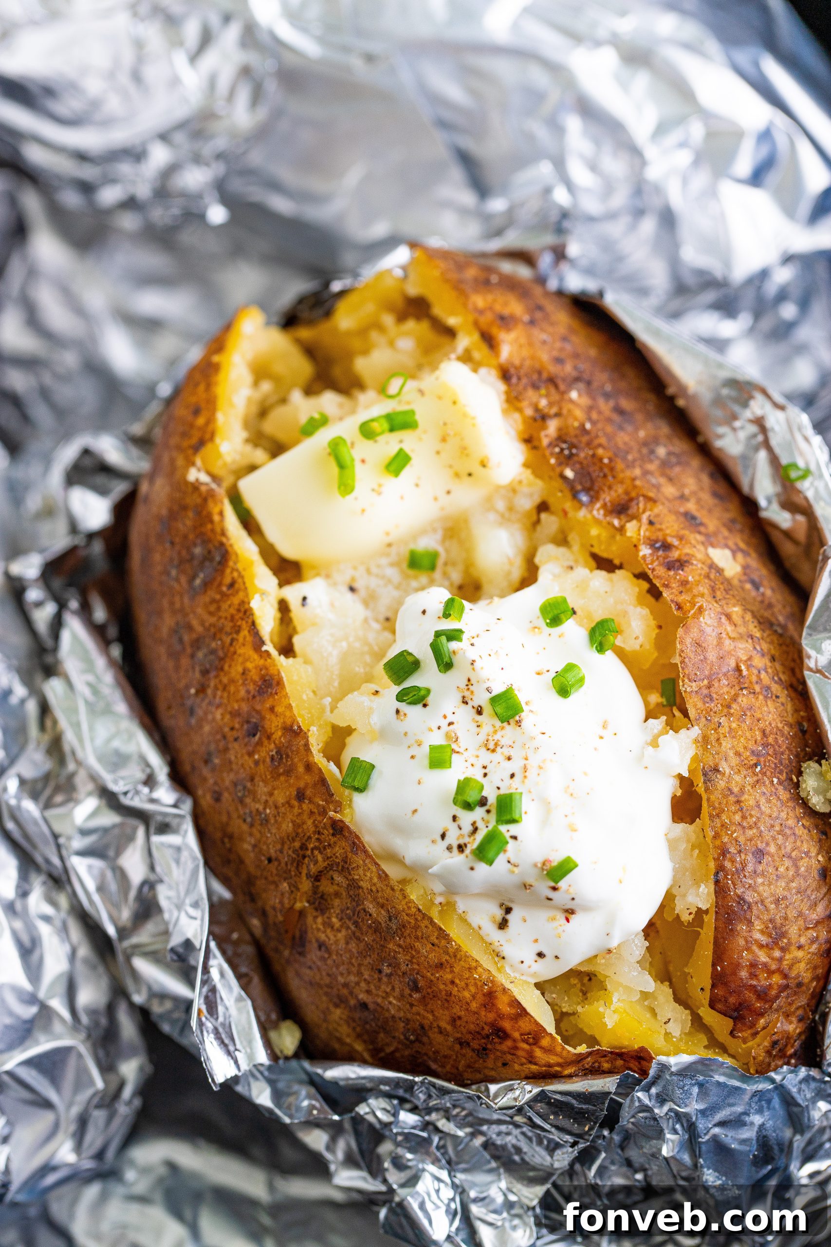 Close-up of a russet potato being pierced multiple times with a fork before cooking