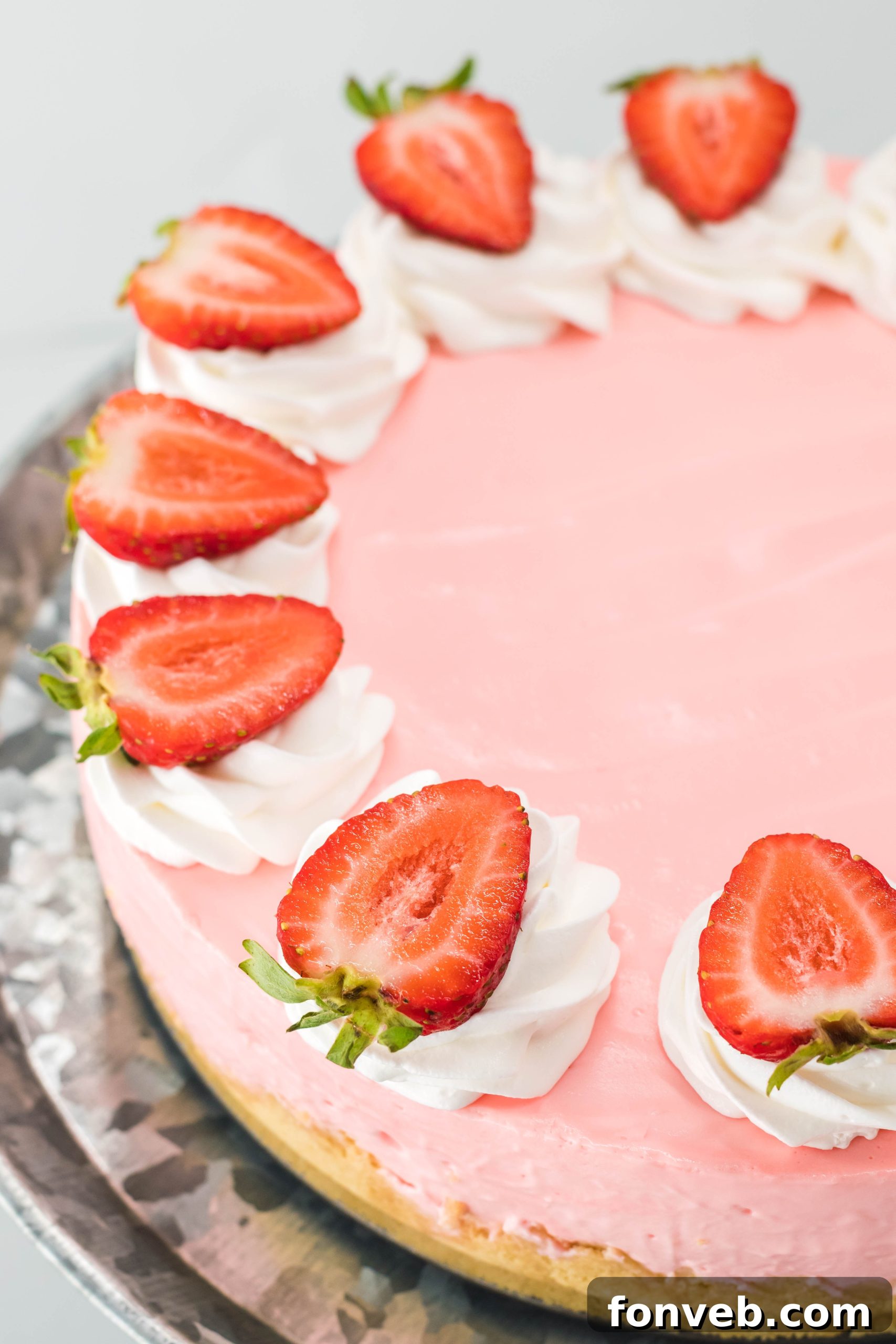 Luscious No-Bake Strawberry Cheesecake 11 A slice of No Bake Strawberry Cheesecake topped with fresh strawberries, blueberries, and whipped cream, ready to be eaten.