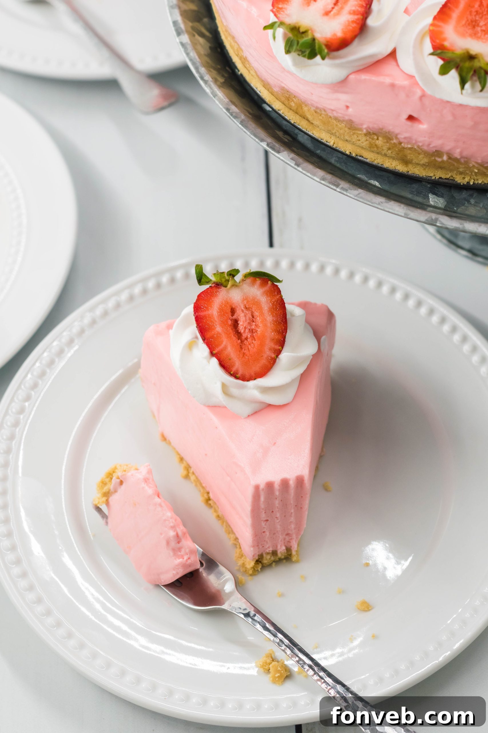 Luscious No-Bake Strawberry Cheesecake 6 A close-up of the smooth, pink cheesecake filling being spread into the crust in a springform pan.