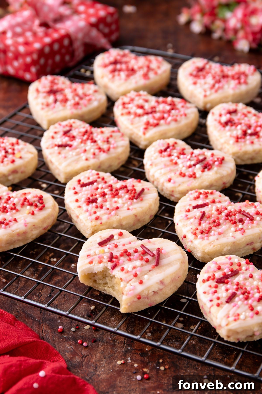 Valentine's Day Shortbread Cookie Bites on a wire cooling rack, with one missing a bite, highlighting their deliciousness.
