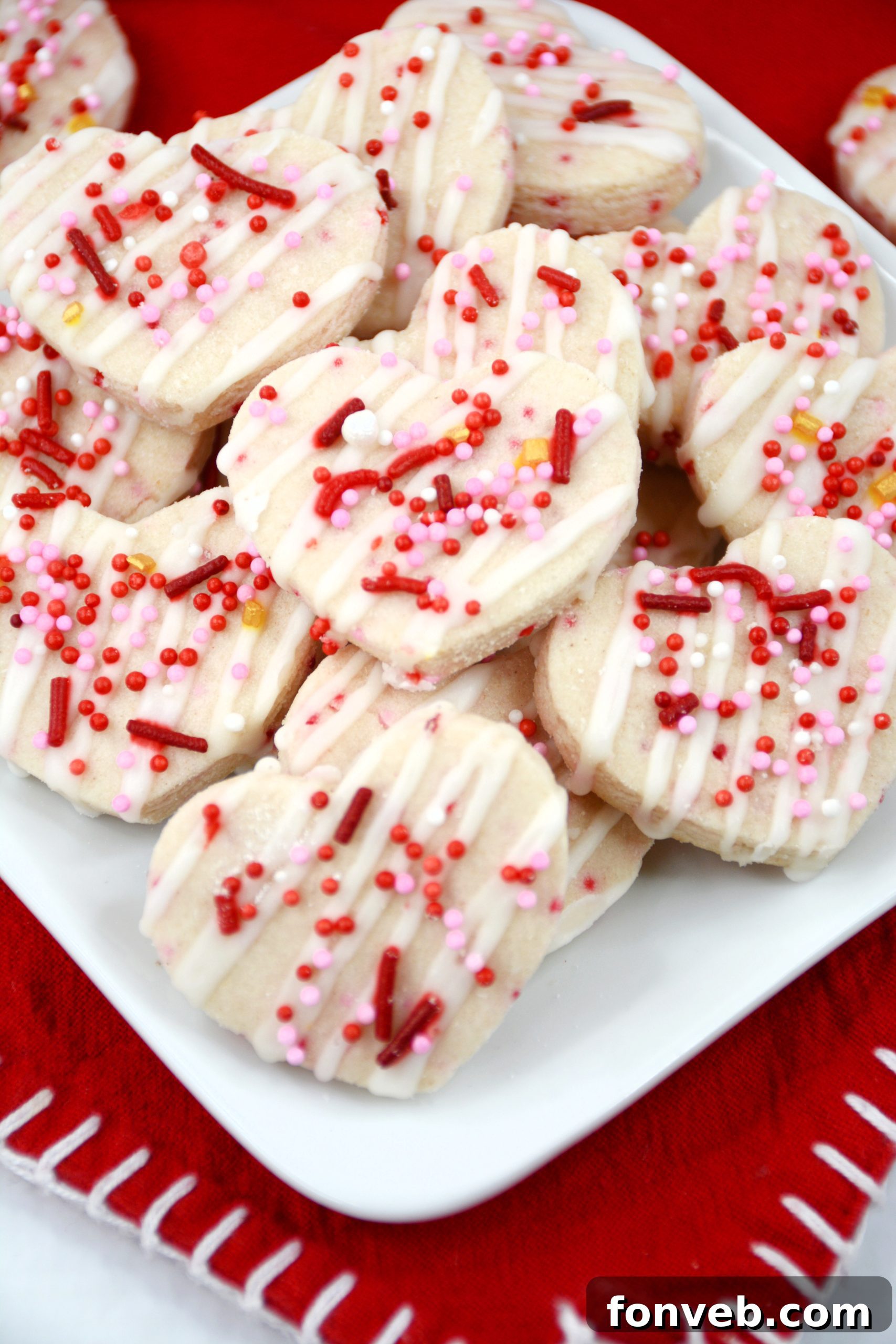 A close-up view of heart-shaped Valentine's Day Shortbread Cookie Bites, showcasing their intricate sprinkle details.