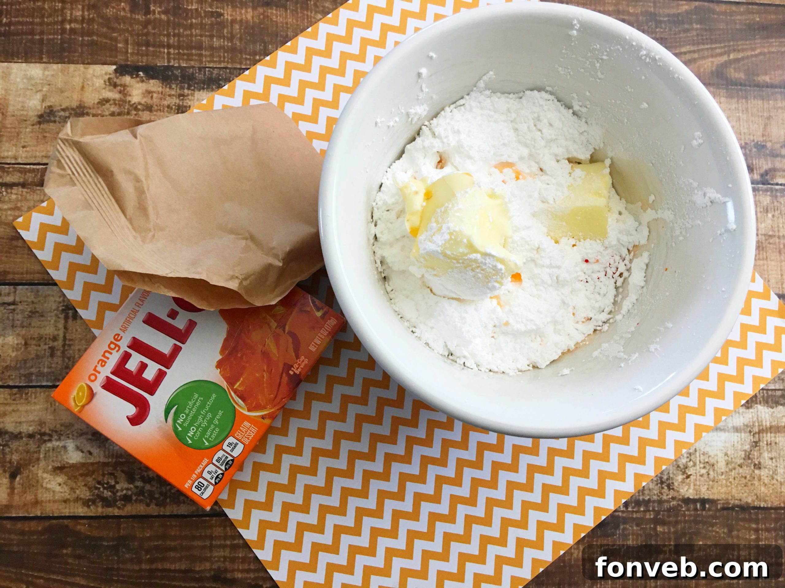 Close-up of a perfectly frosted Orange Creamsicle cupcake with a white paper straw.