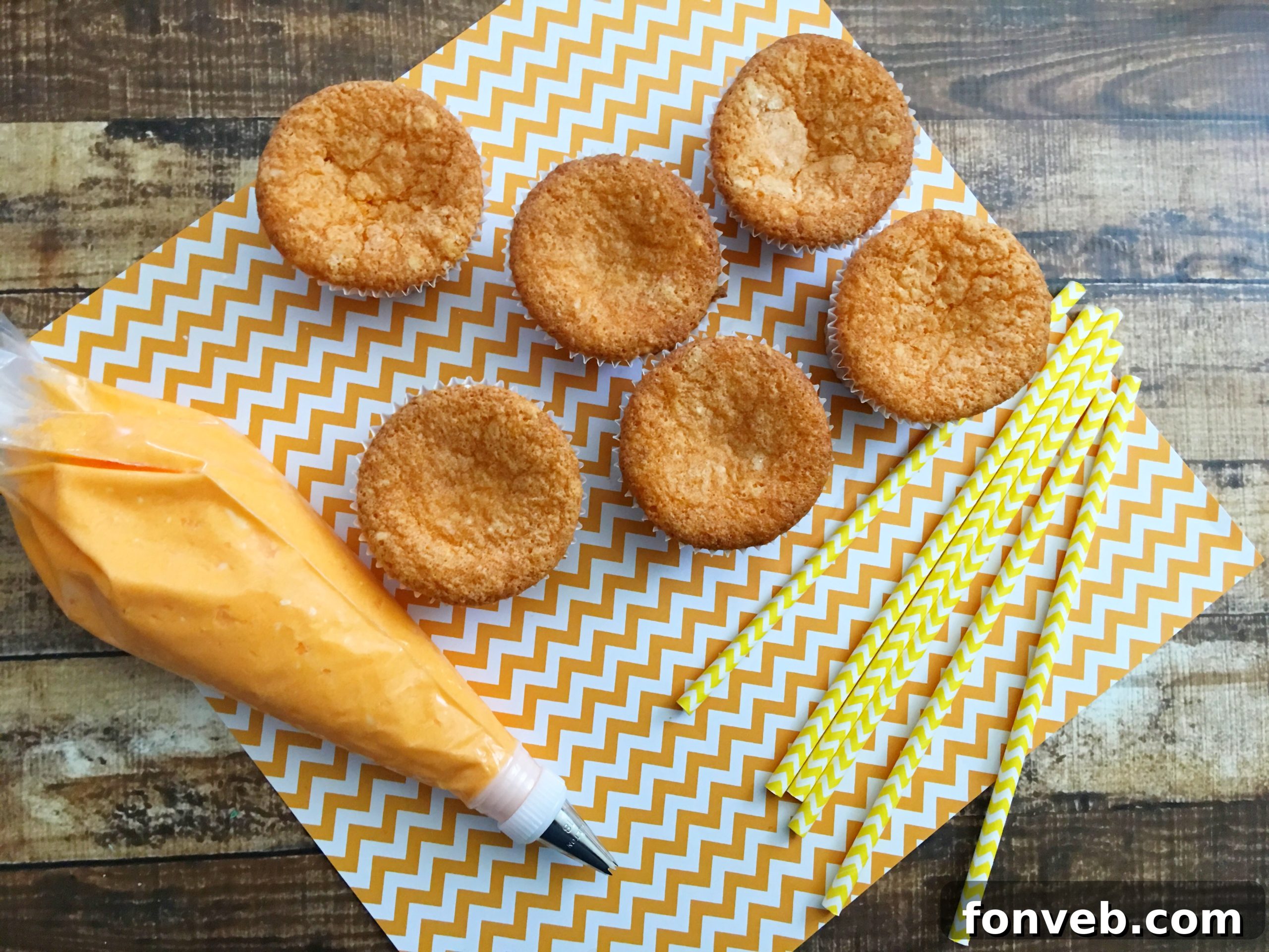 A close-up of a beautifully frosted Orange Creamsicle Cupcake with a paper straw.