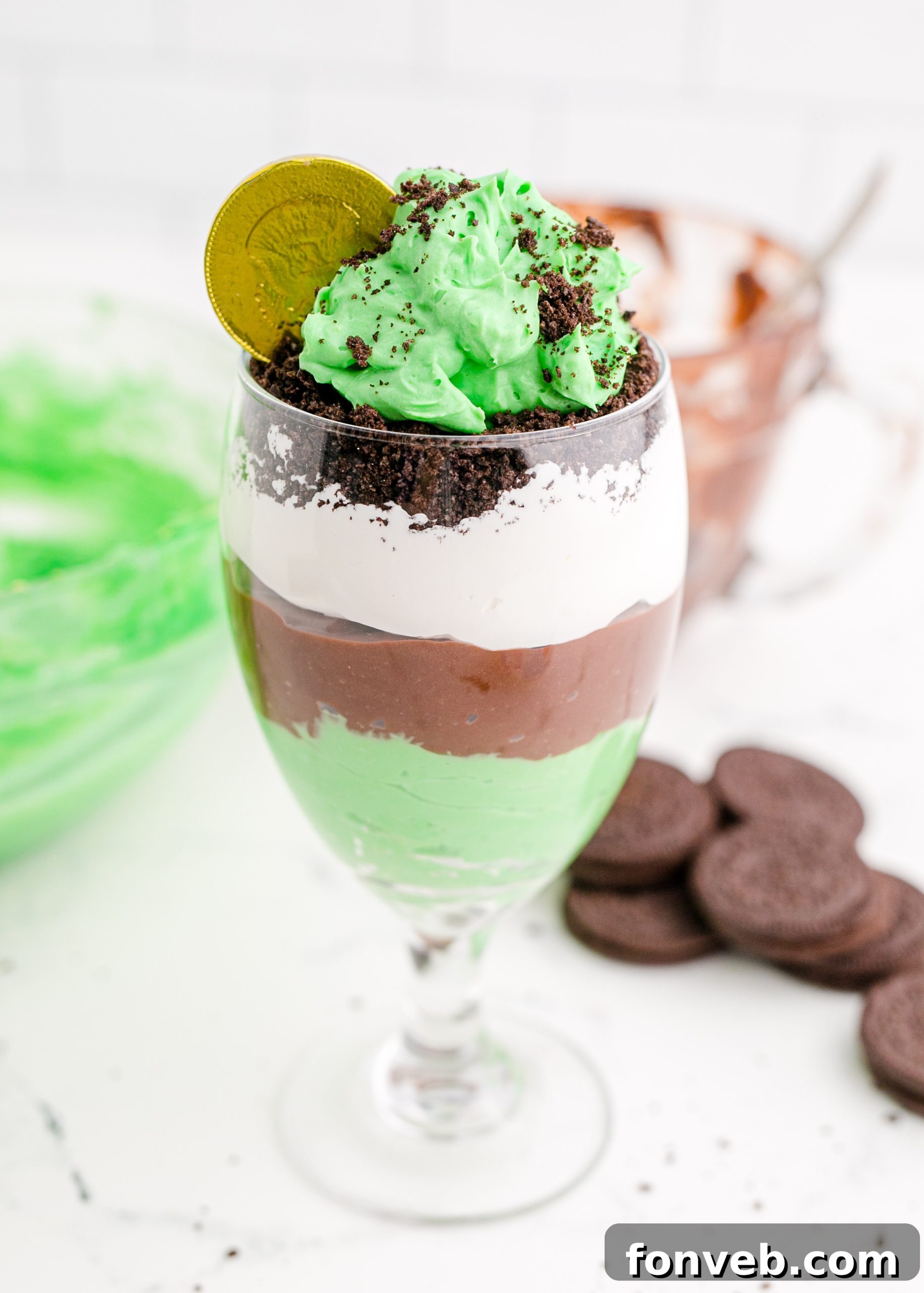 St. Patrick's Day Pudding Cups with green and chocolate layers, topped with whipped cream, sprinkles, and a gold coin