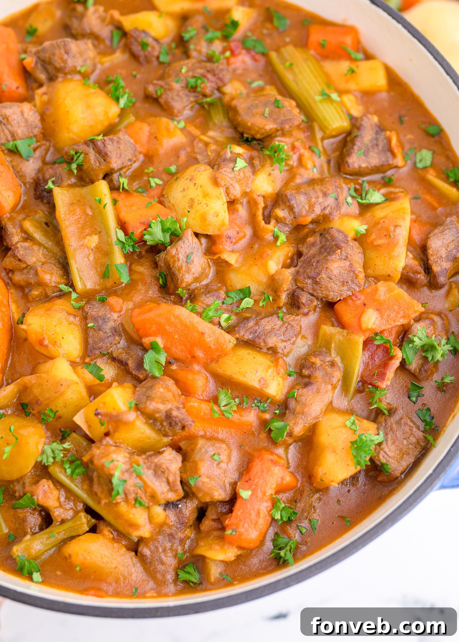 Hearty Guinness Beef Stew in a dutch oven, garnished with fresh herbs