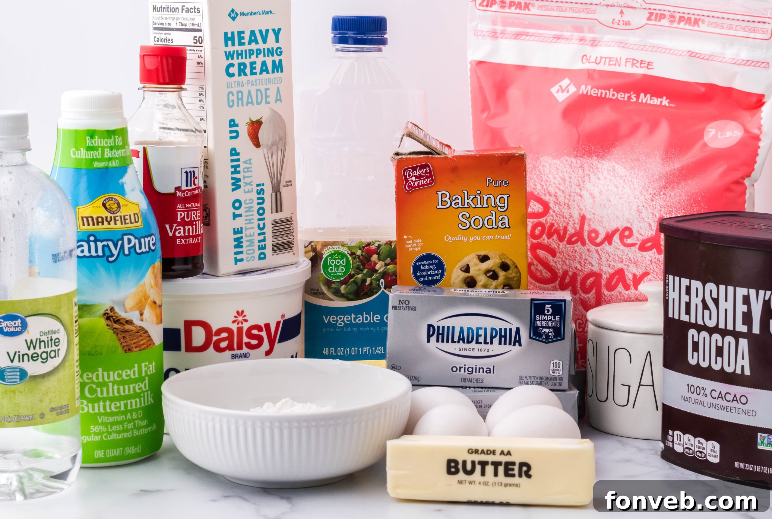 A full Red Velvet Cheesecake Cake on a stand, decorated with cream cheese frosting and a dusting of chocolate shavings.