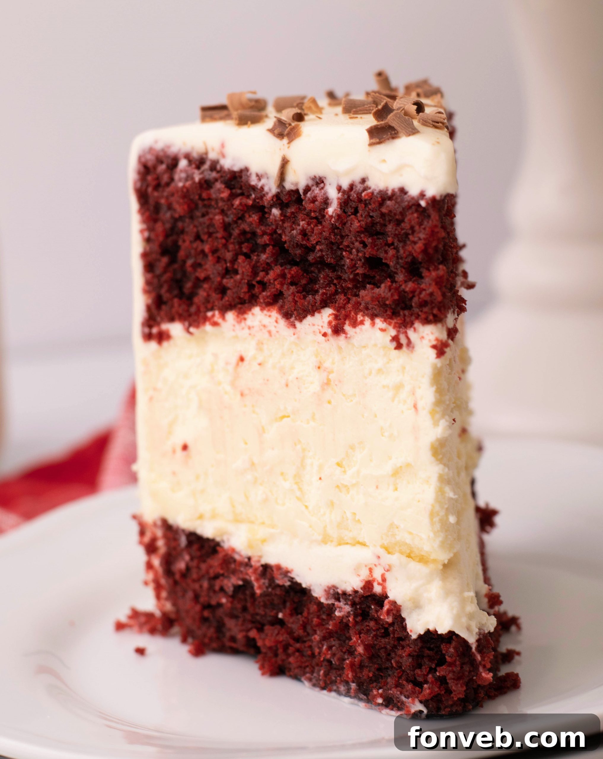 Hands frosting a Red Velvet Cheesecake Cake, showing the cream cheese frosting being applied smoothly.