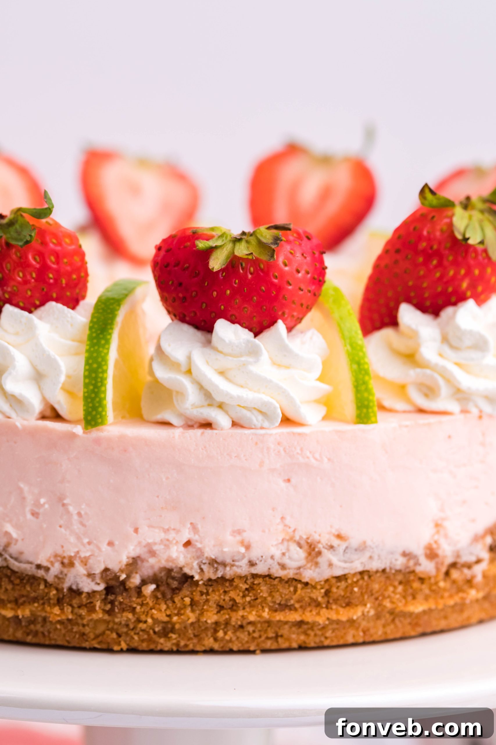 A whole Instant Pot Strawberry Daiquiri Cheesecake garnished with fresh strawberries and lime slices.