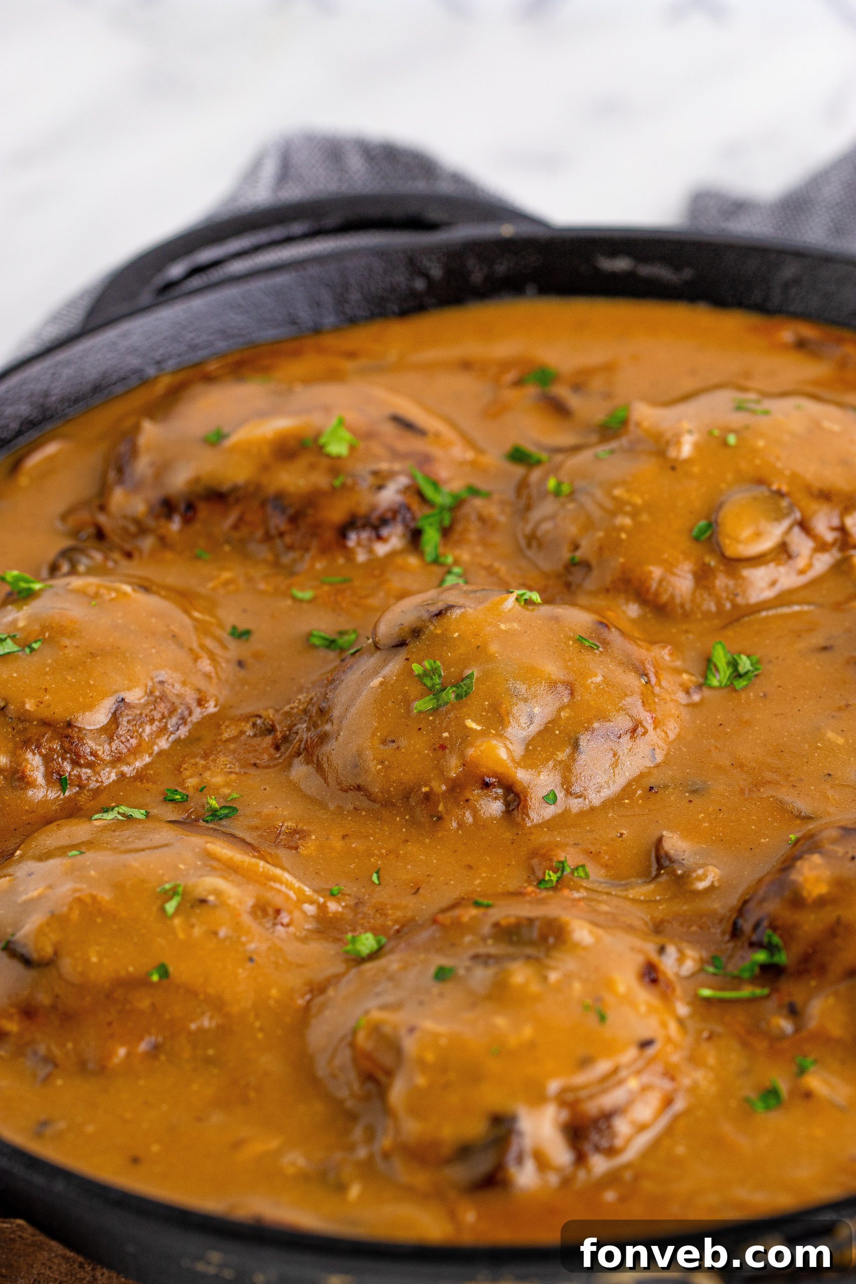 Hearty Salisbury Steaks with Rich Gravy 5 Overhead shot of two Salisbury Steaks generously covered in mushroom gravy, served on a white plate.