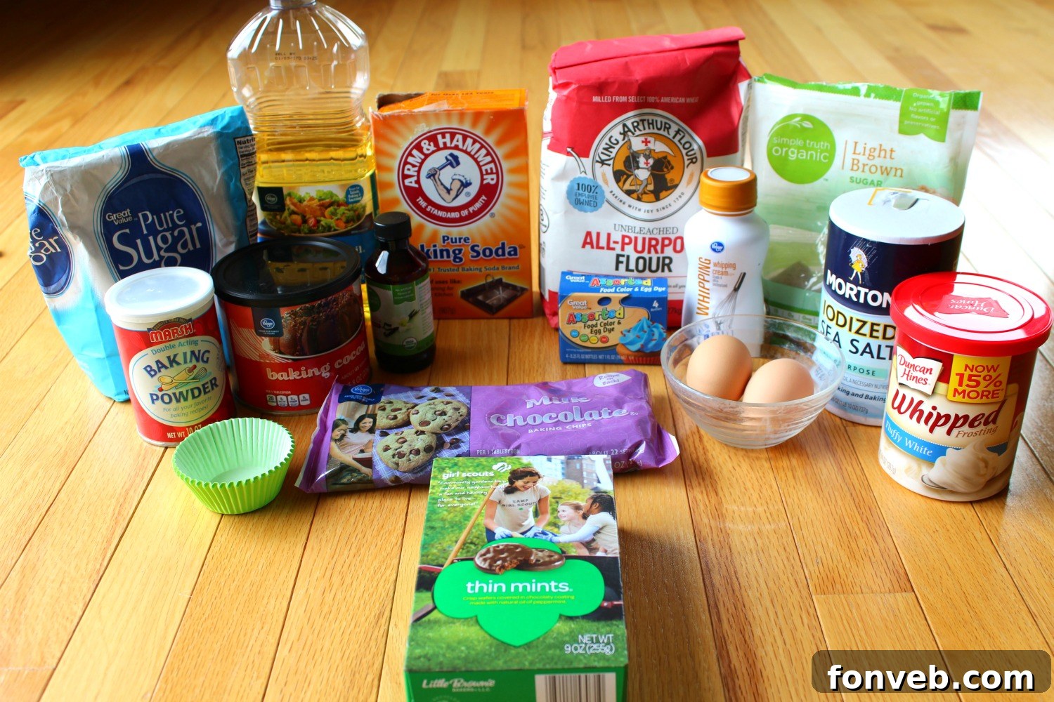 Ingredients for Thin Mint Cupcakes laid out on a kitchen counter, including eggs, sugar, flour, cocoa powder, milk, and chocolate chips.