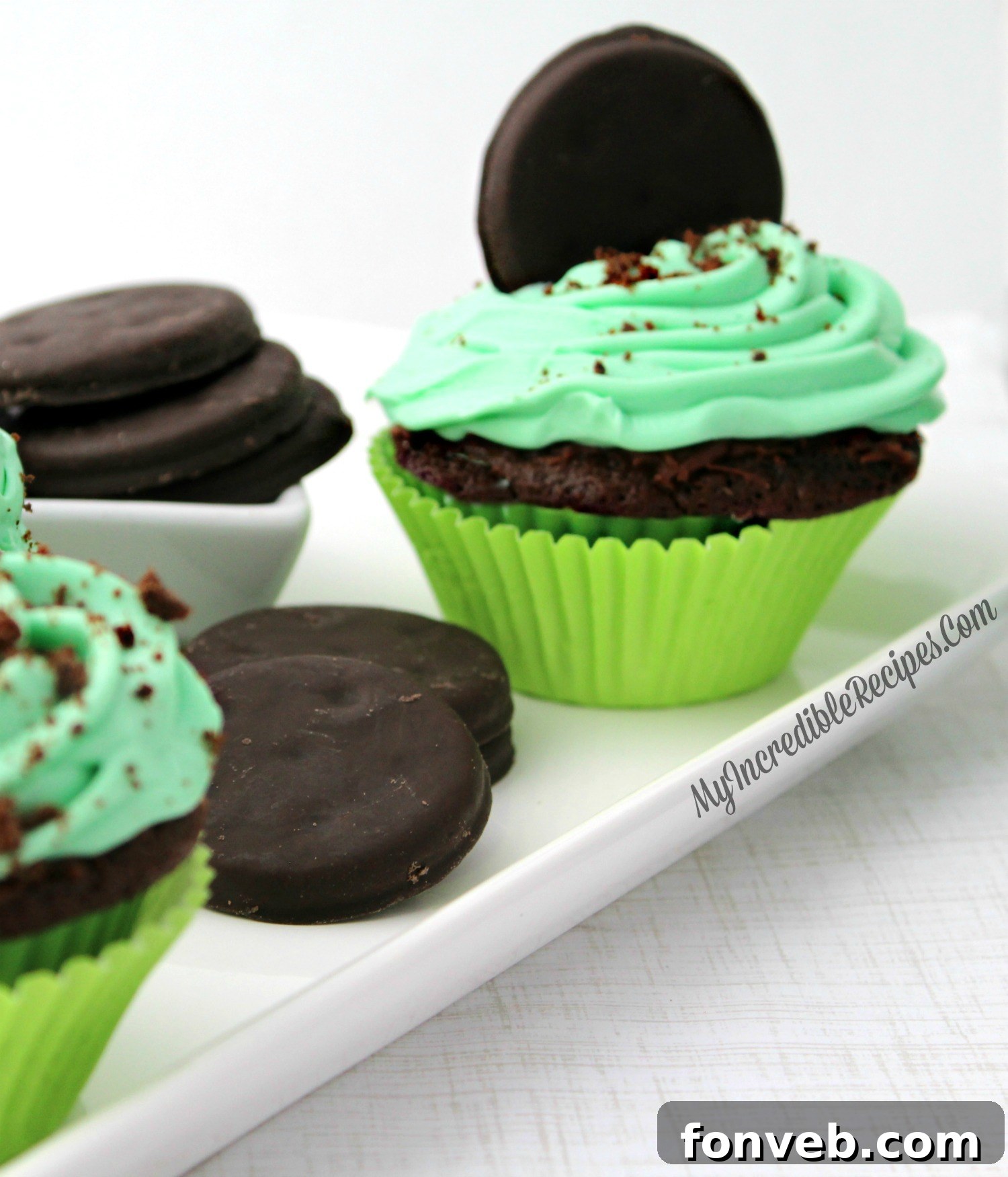 A close-up shot of the perfectly swirled green mint frosting on a Thin Mint cupcake, adorned with a cookie.