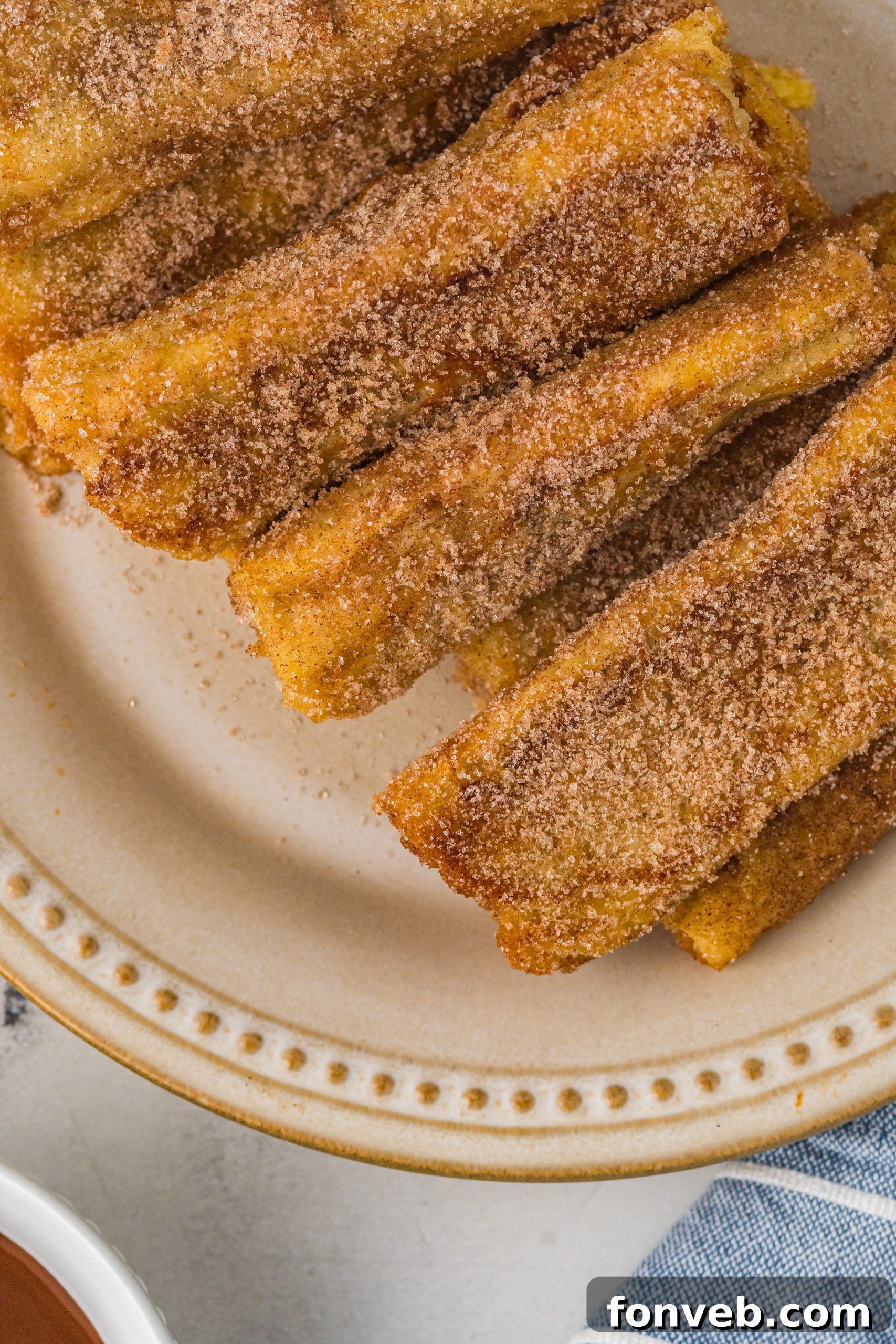 A plate of perfectly arranged Churro French Toast Roll Ups, inviting diners to indulge.