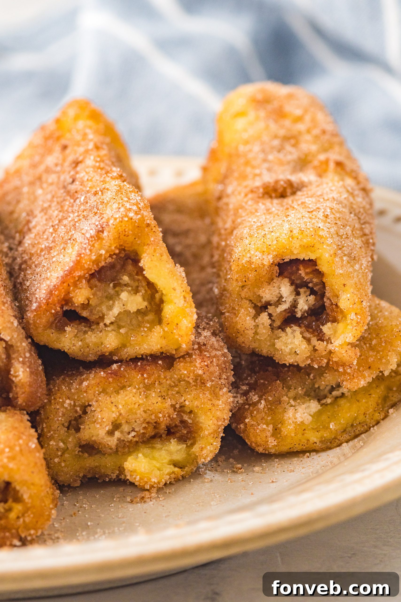 Freshly cooked Churro French Toast Roll Ups cooling slightly on a wire rack, covered in cinnamon sugar.