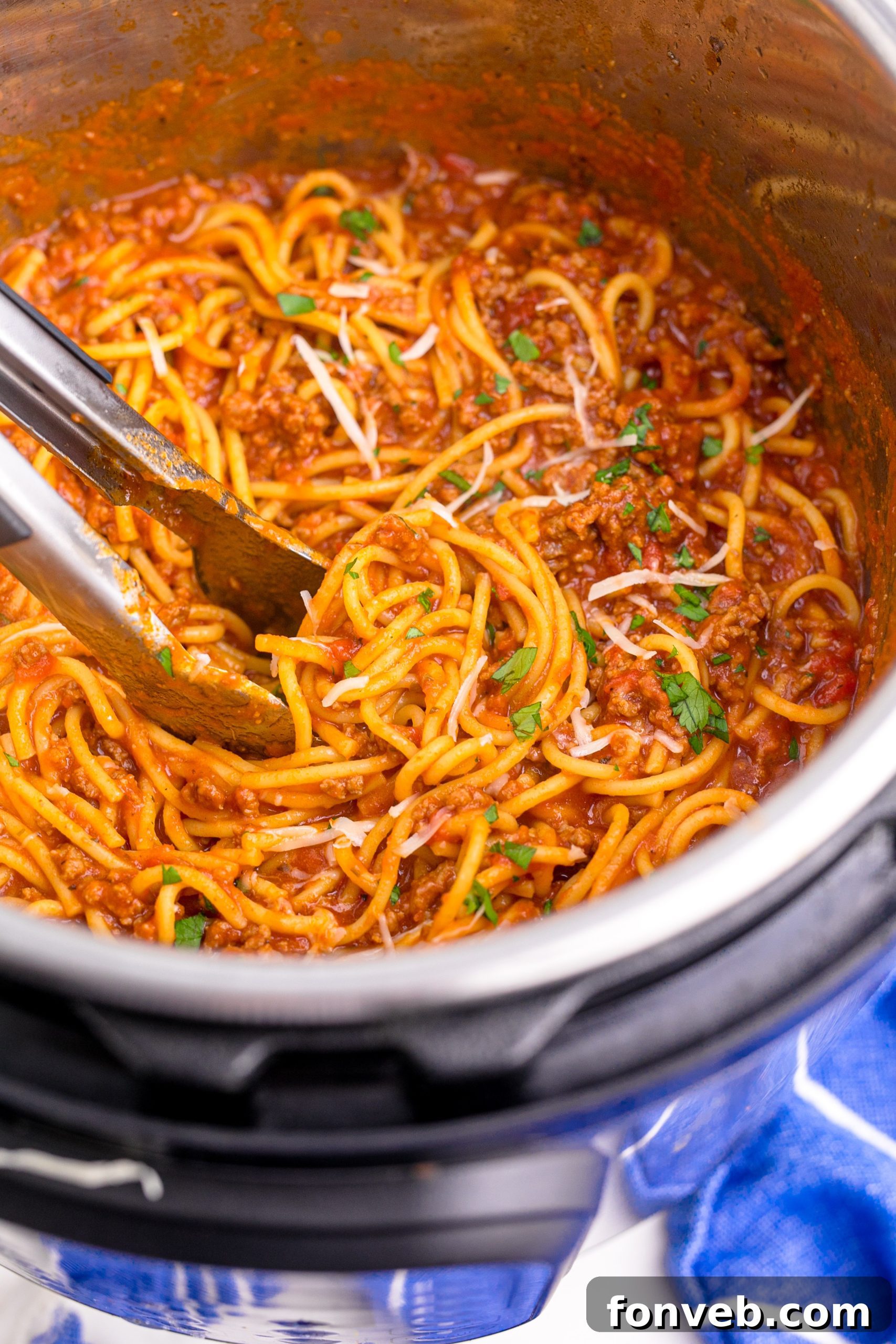 Instant Pot Spaghetti being mixed with tongs, covered in parmesan cheese