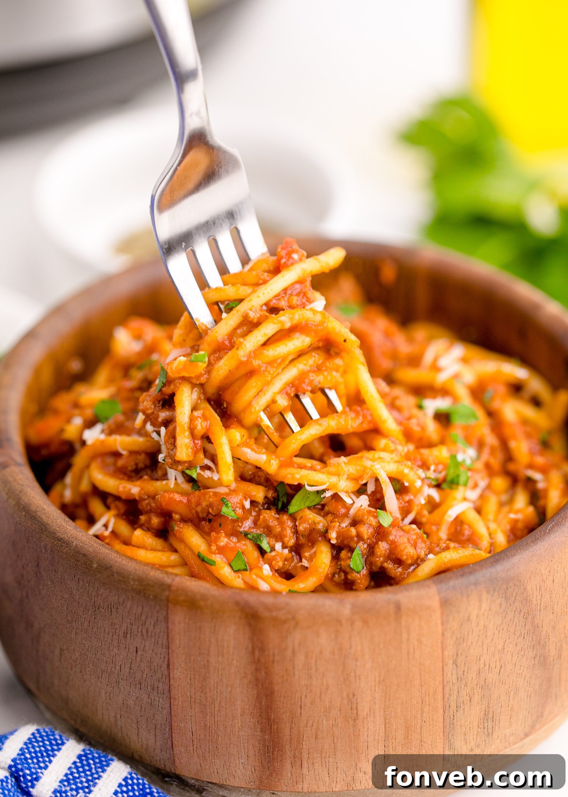 Instant Pot Spaghetti in a wooden bowl with a fork lifting the spaghetti up