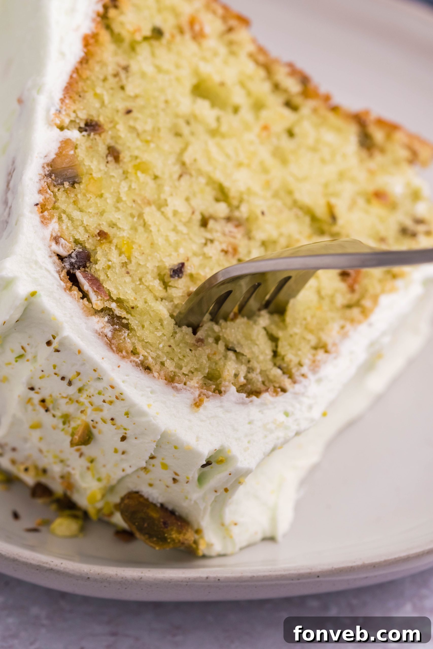 Pistachio Cake slice on a plate with a fork going into it