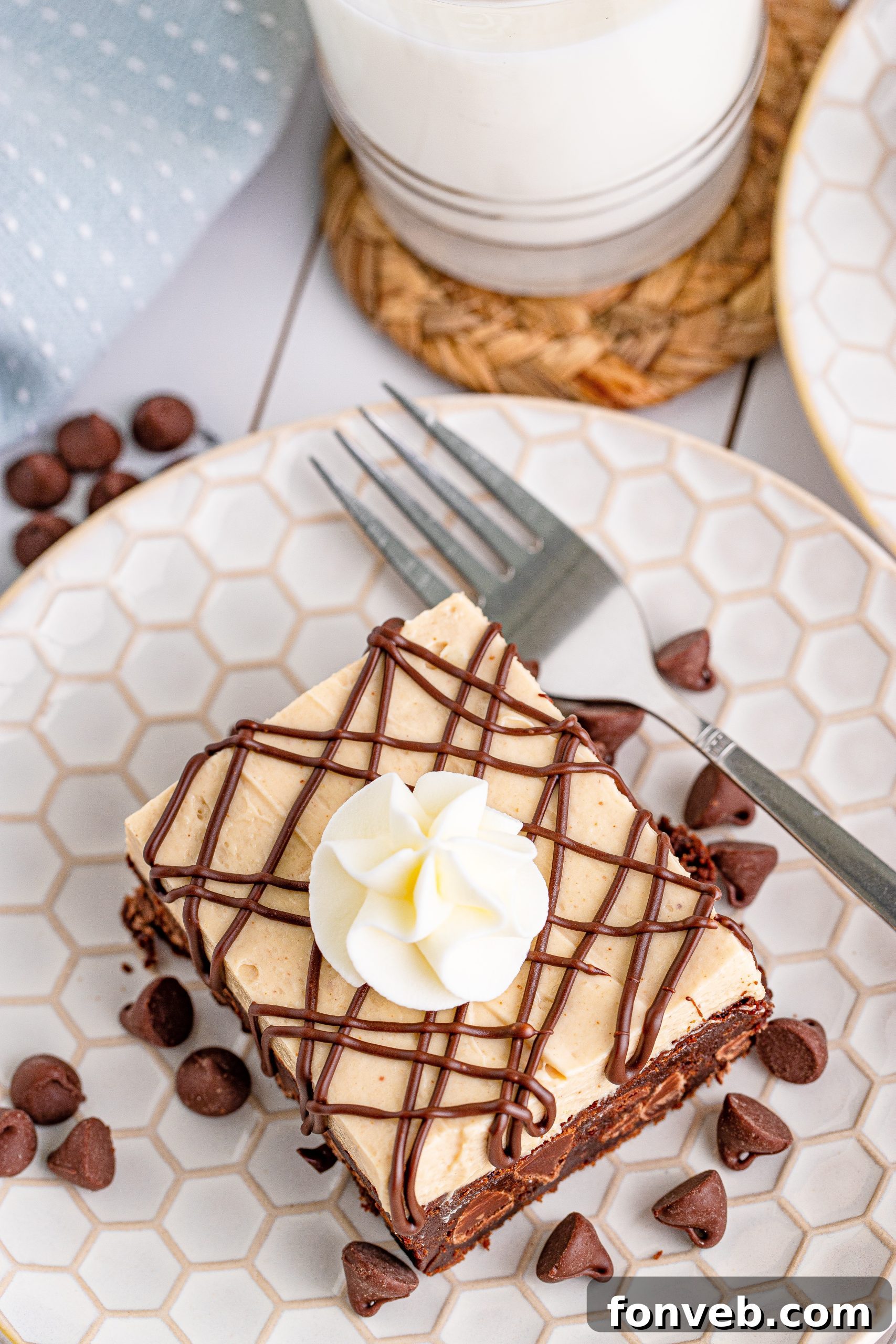 overhead shot of Peanut Butter Brownies on a white place drizzled with chocolate and topped with whipped cream