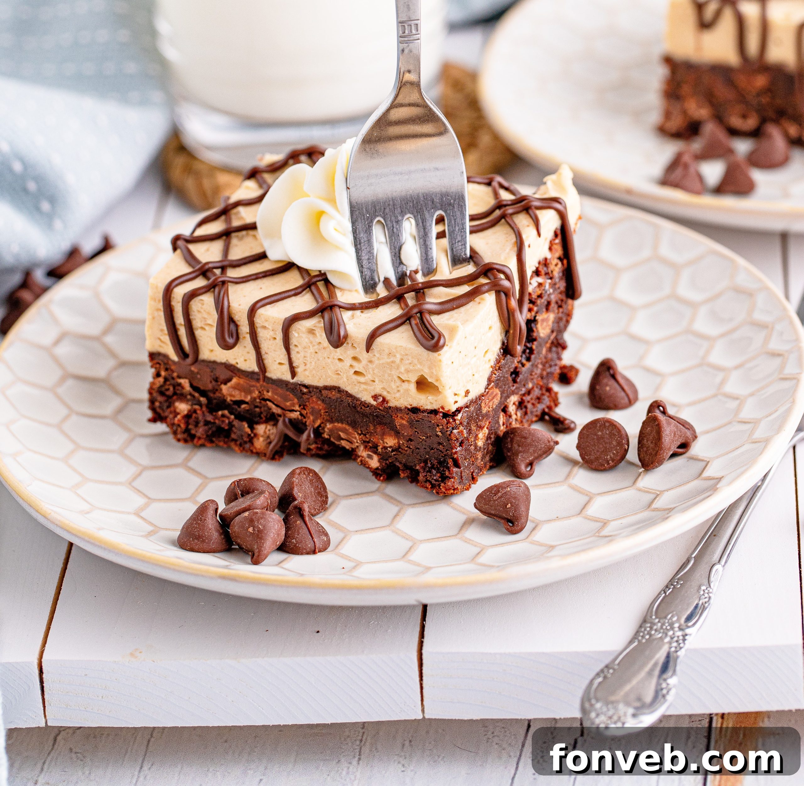 Peanut Butter Brownies on a white place drizzeled with chocolate and topped with whipped cream with a forn going through the brownie