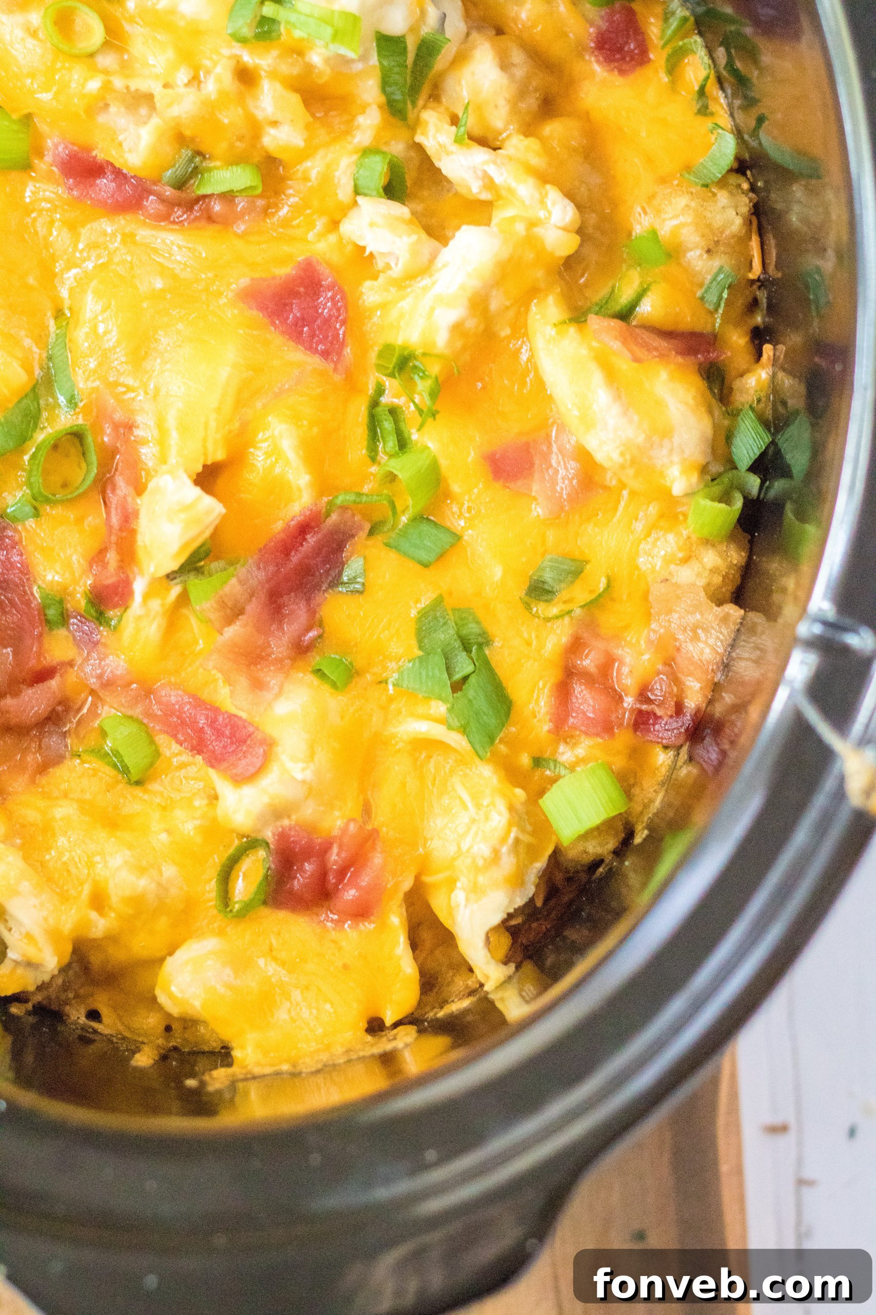 Tater Tot Casserole in the crock pot covered in melty cheese, almost ready