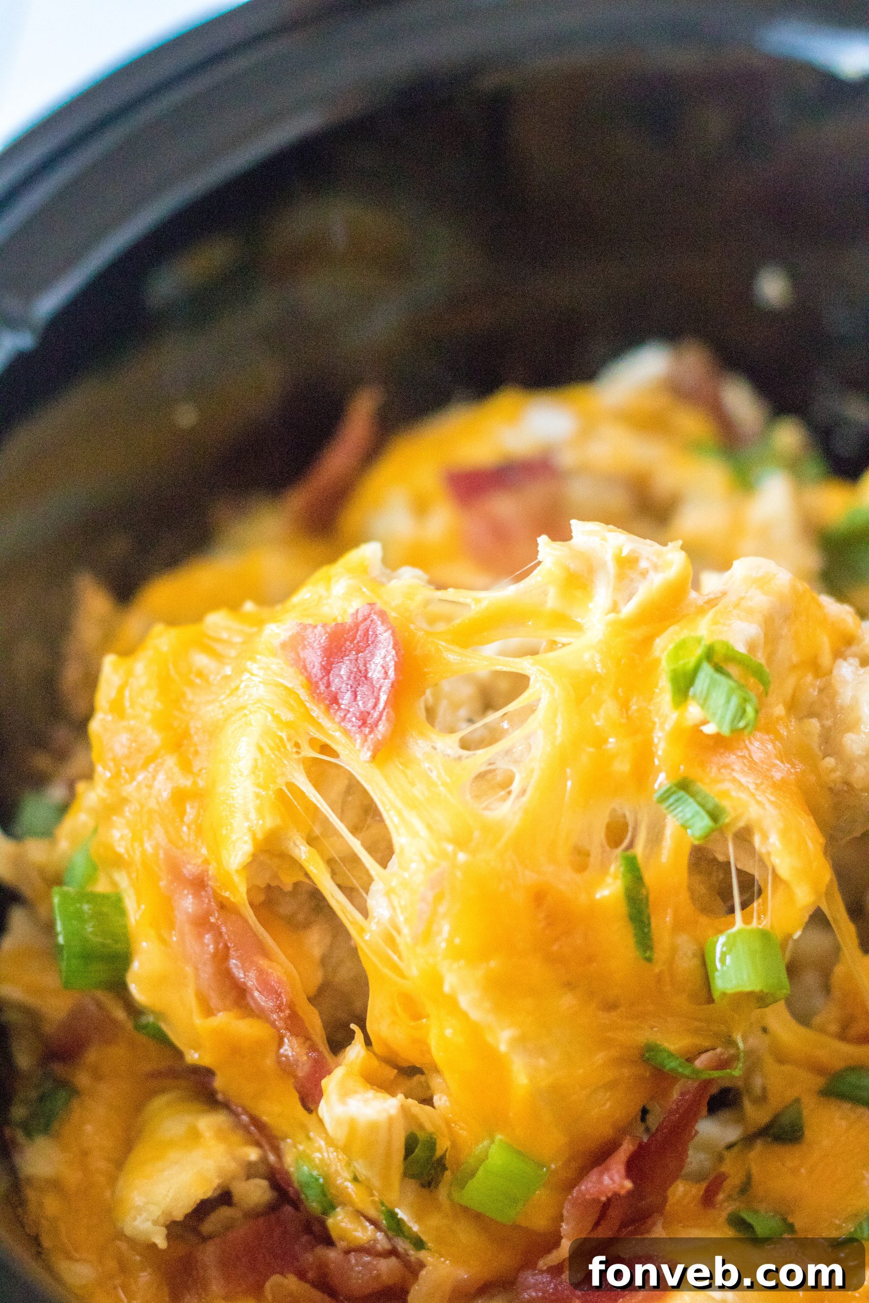 Tater Tot Casserole in the crock pot on a spoon, steaming hot