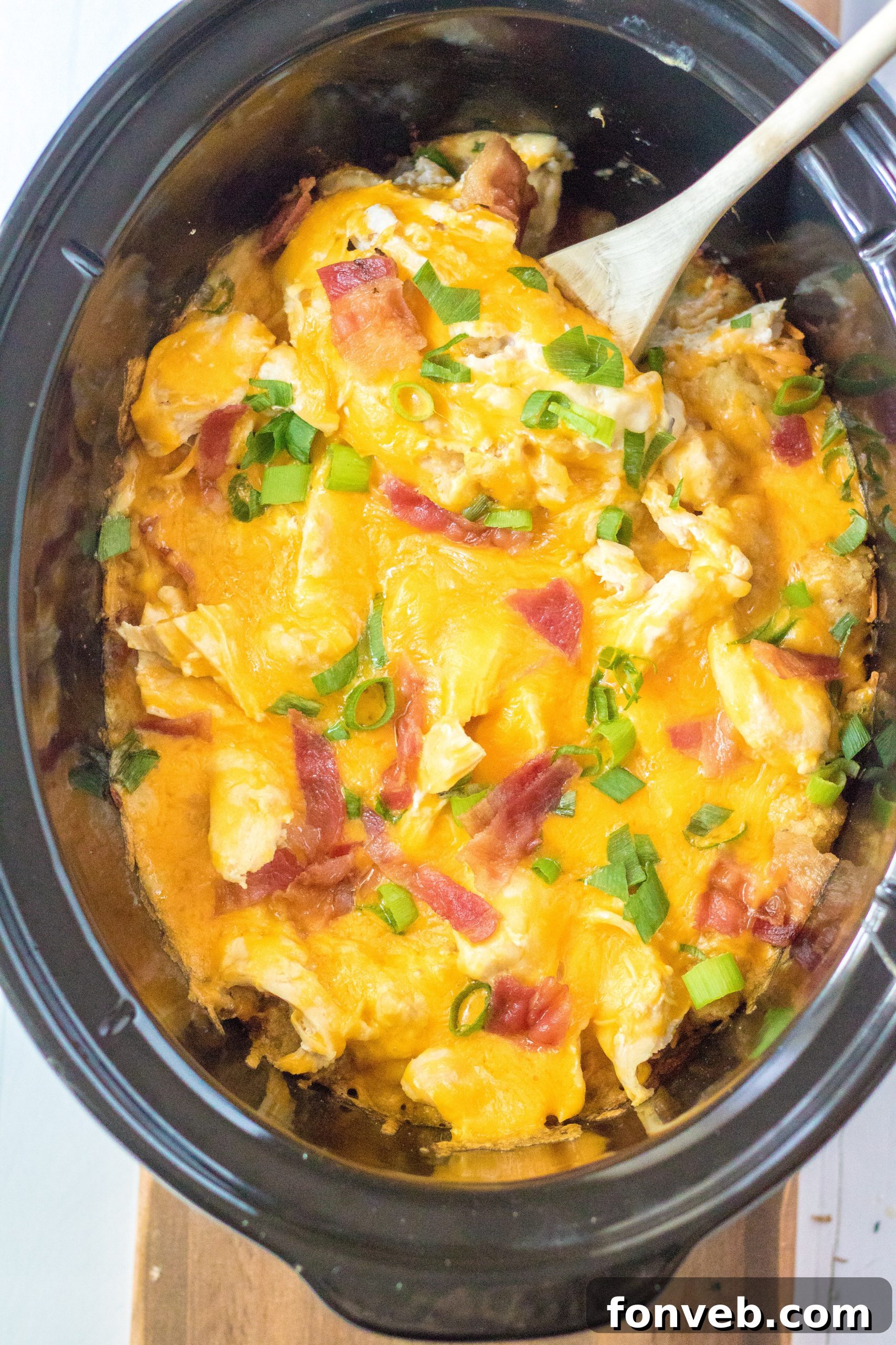 Tater Tot Casserole in the crock pot with a spoon in it, showcasing the layers