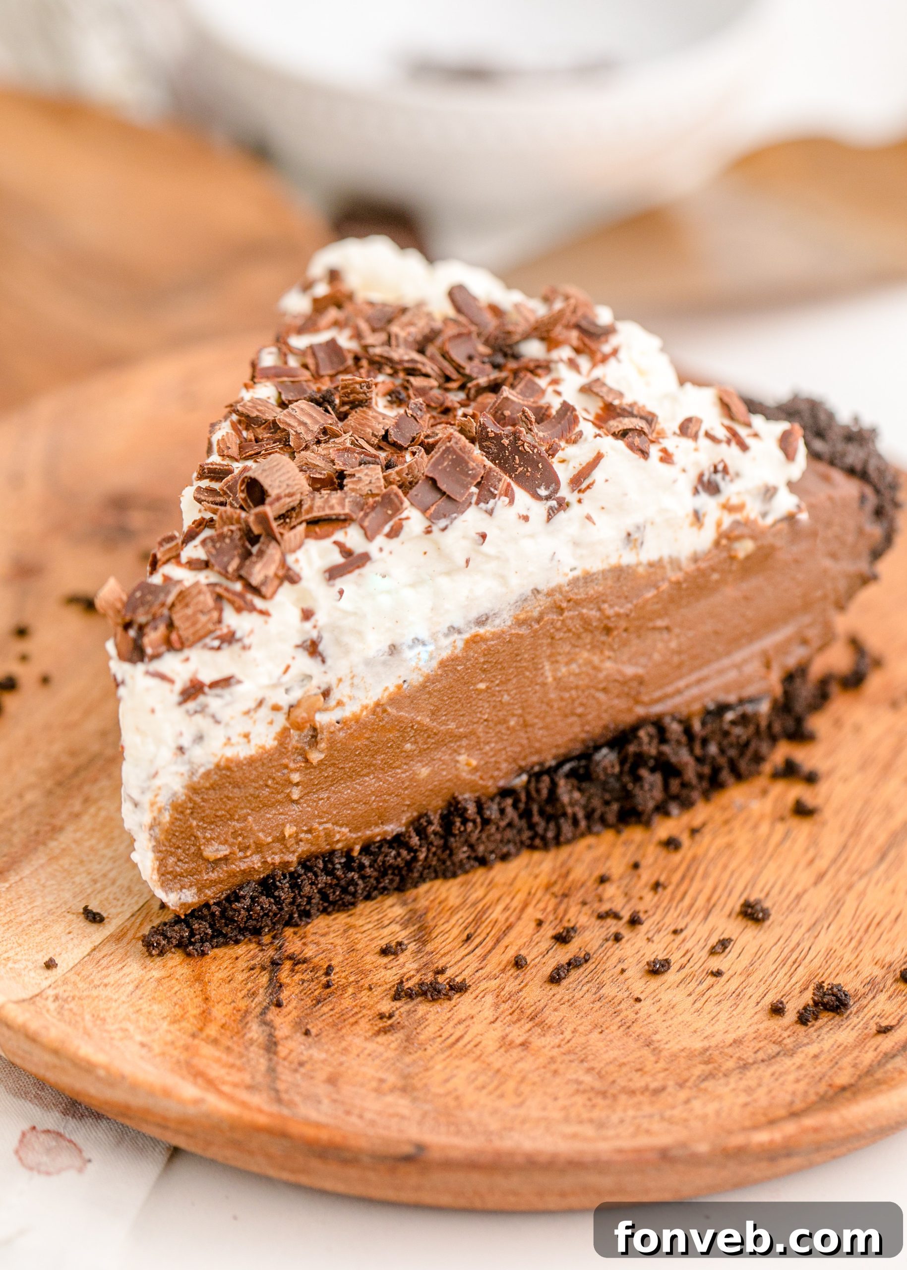 Velvet Chocolate Dream 11 Chocolate Cream Pie topped with whipped cream and chocolate shavings on a brown cutting board, with a clear view of the crust