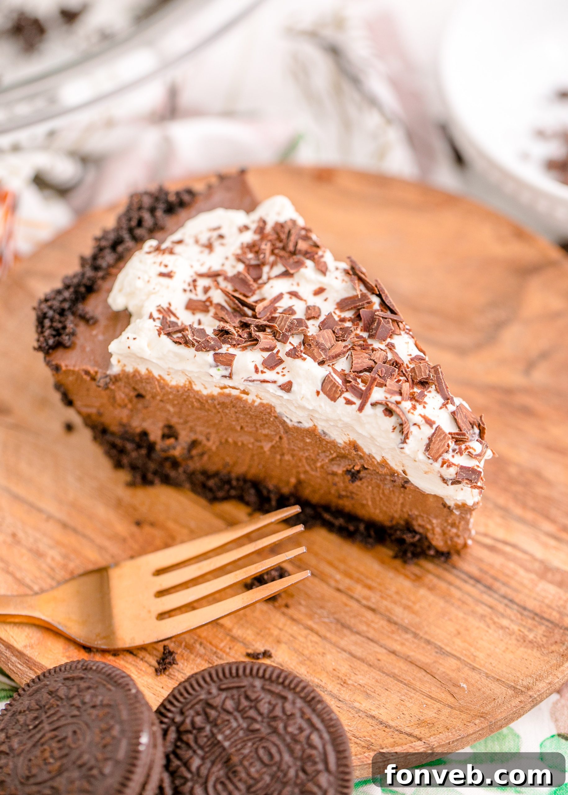 Velvet Chocolate Dream 15 Chocolate Cream Pie topped with whipped cream and chocolate shavings on a brown cutting board, showcasing its freshness