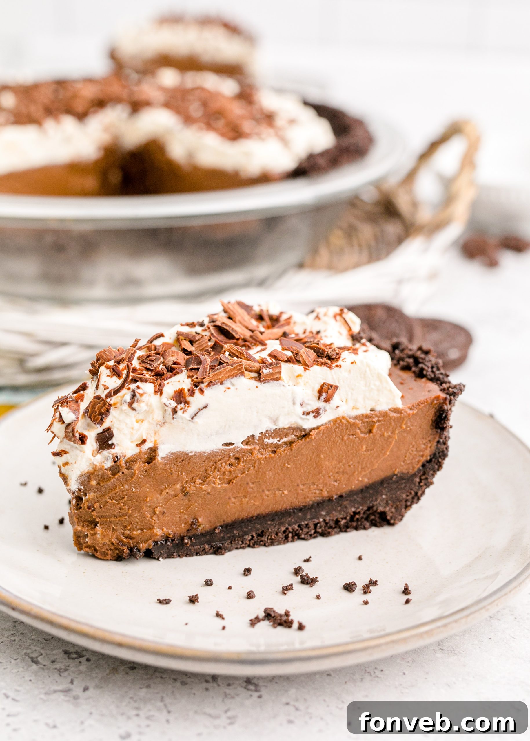Velvet Chocolate Dream 18 Chocolate Cream Pie topped with whipped cream and chocolate shavings on a white plate, ready to be enjoyed