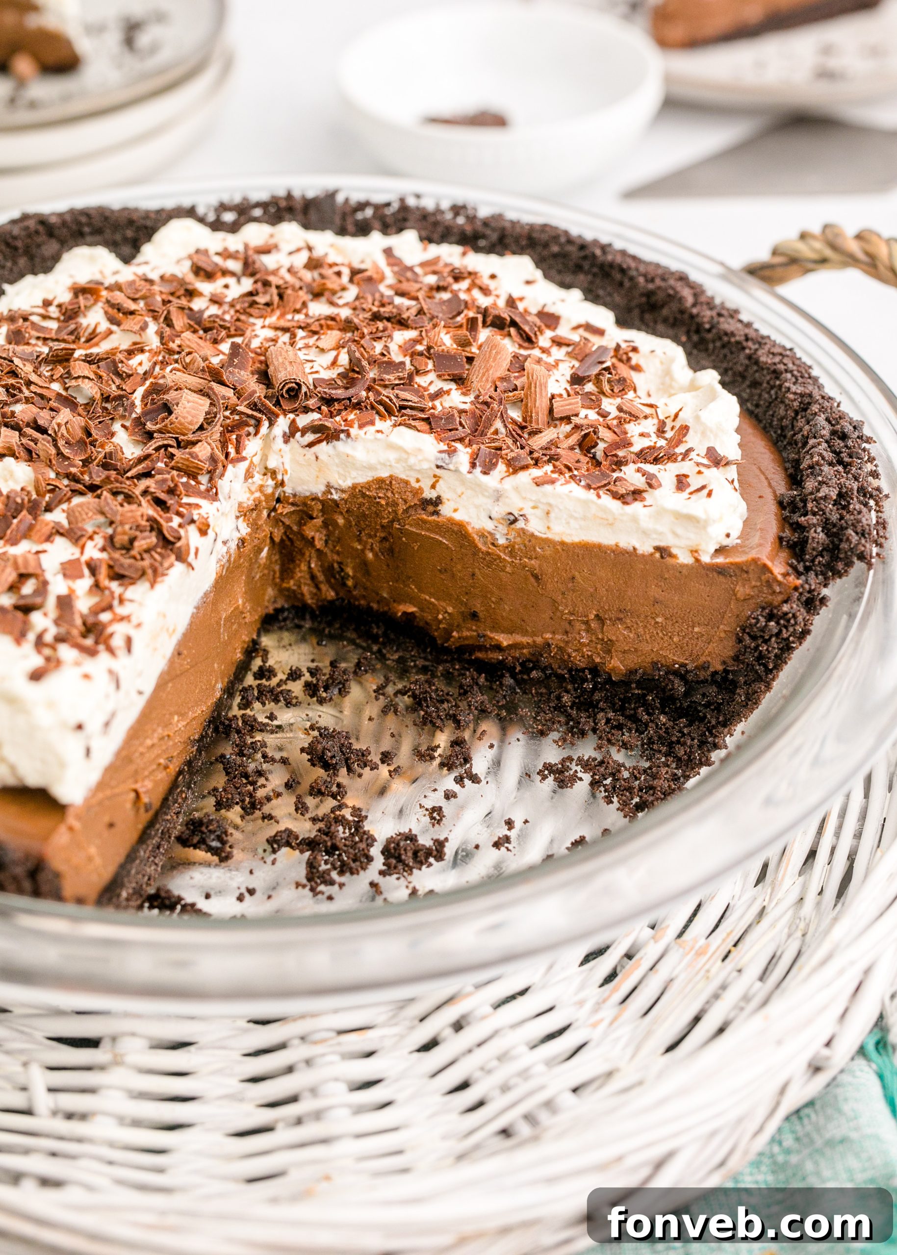 Velvet Chocolate Dream 19 Chocolate Cream Pie topped with whipped cream and chocolate shavings in a white pie dish with a slice taken out, highlighting its rich texture